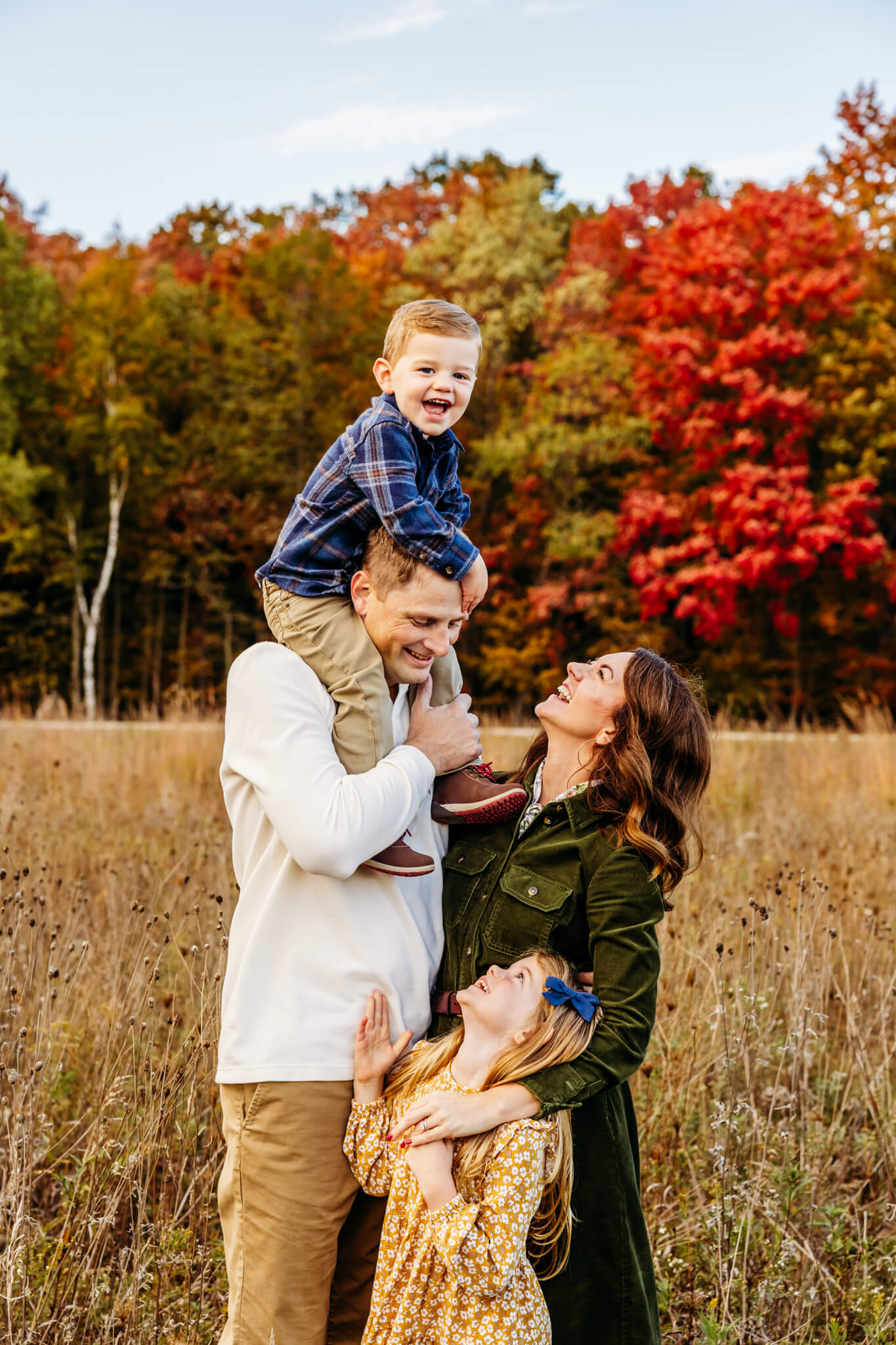 Dad holding his son on his shoulders as mom wraps her arms around daughter and they look up laughing for a post about Toy Stores in Milwaukee Wi