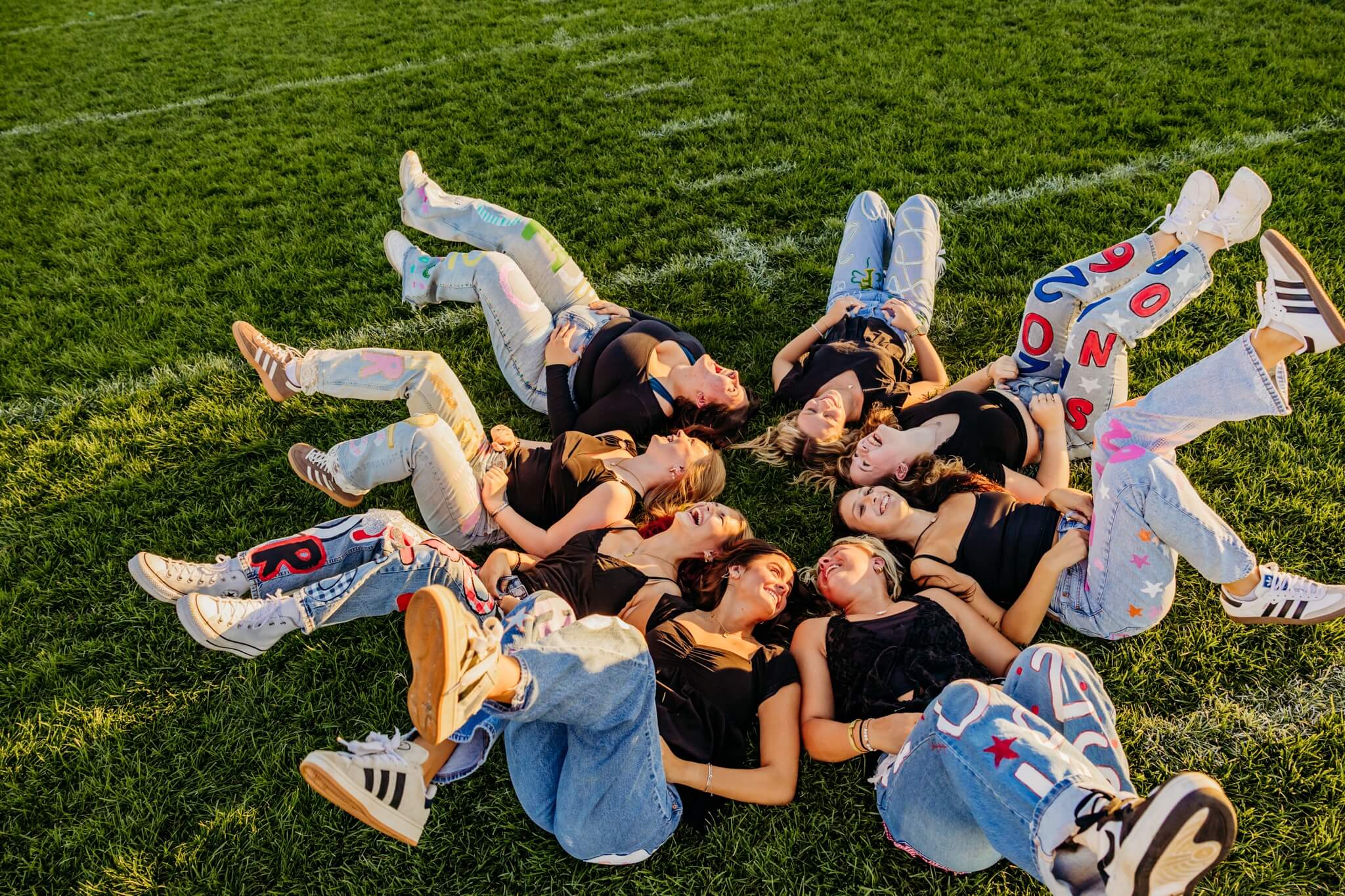 Eight teen girls laying on their backs and kicking their feet in the air for a post about High Schools in Green Bay.