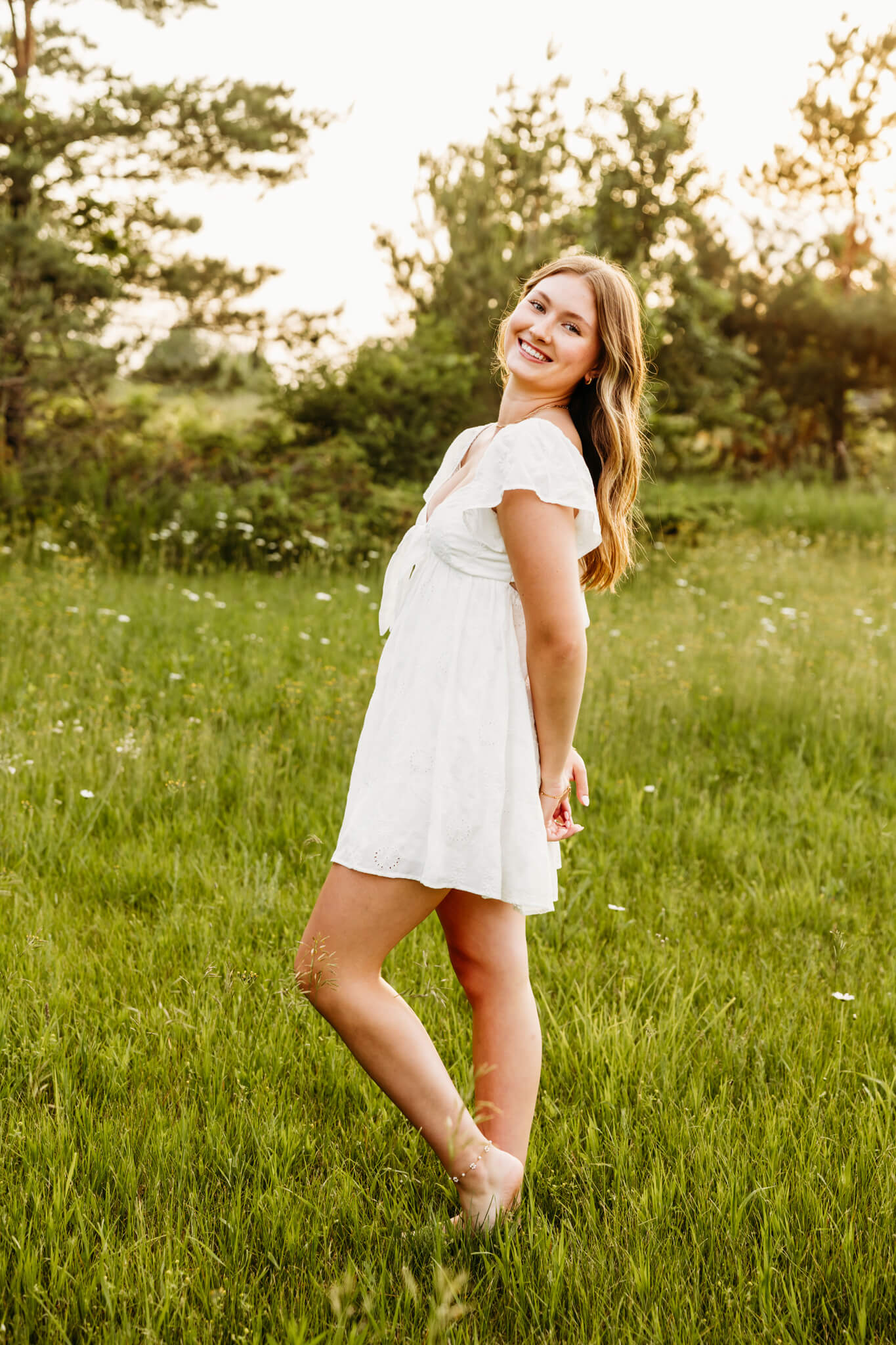 Gorgeous young lady wearing a short white dress standing in a grassy field near Egg Harbor.