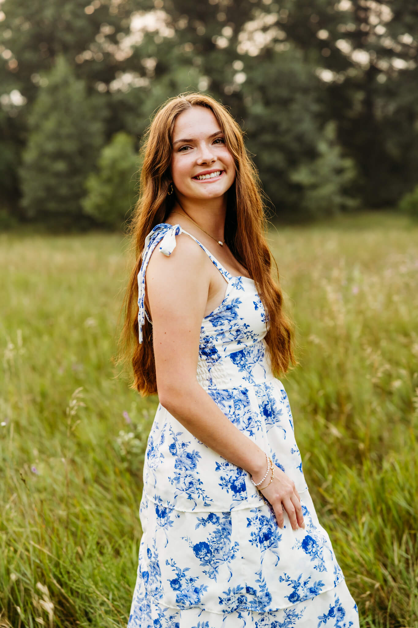 Teen girl in a white and blue dress looking over her shoulder and smiling for her yearbook photo for Preble High School in Green Bay Wi.