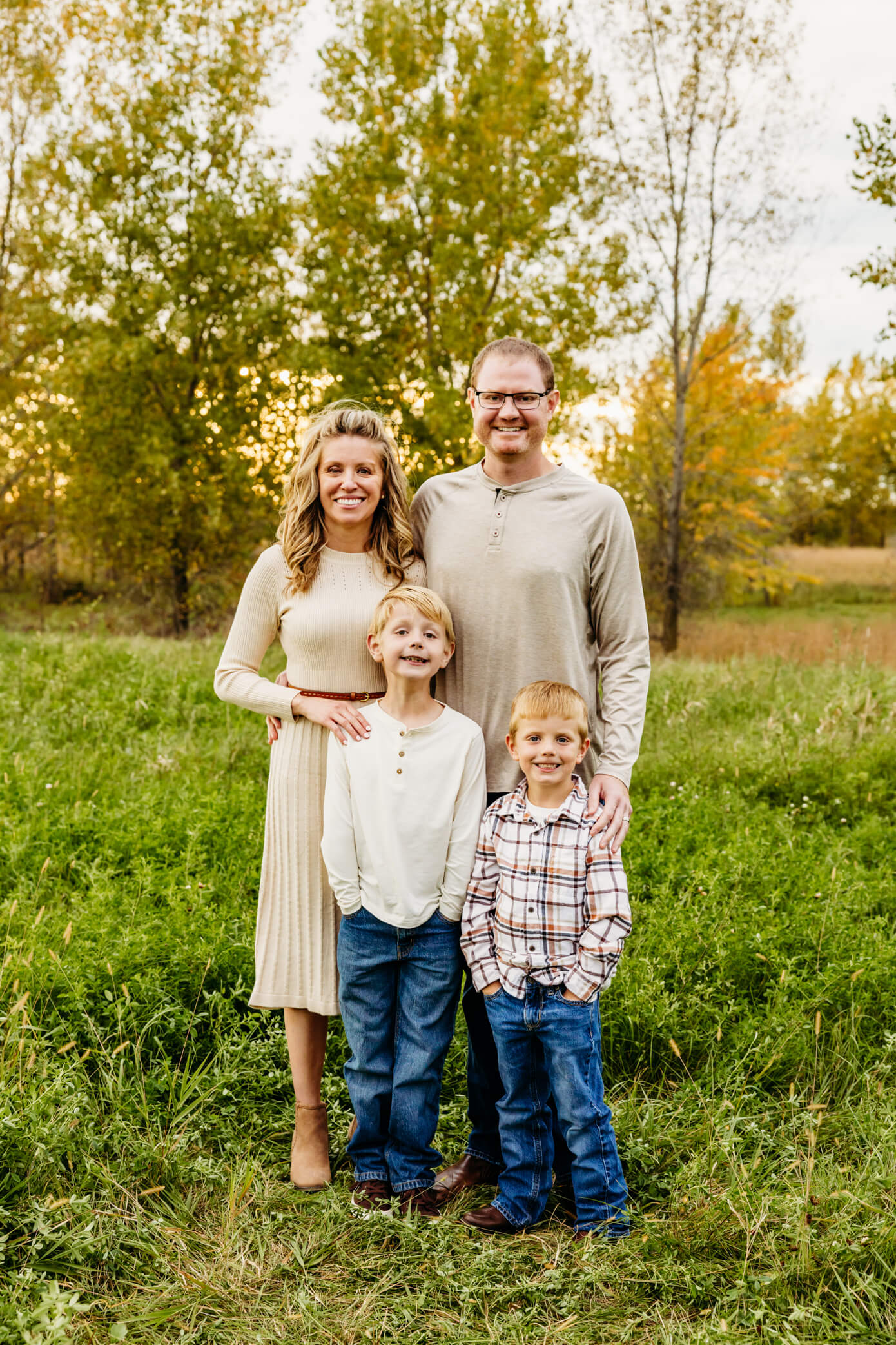 Mom and dad standing with their two sons in a field at a pumpkin patch in Door County
