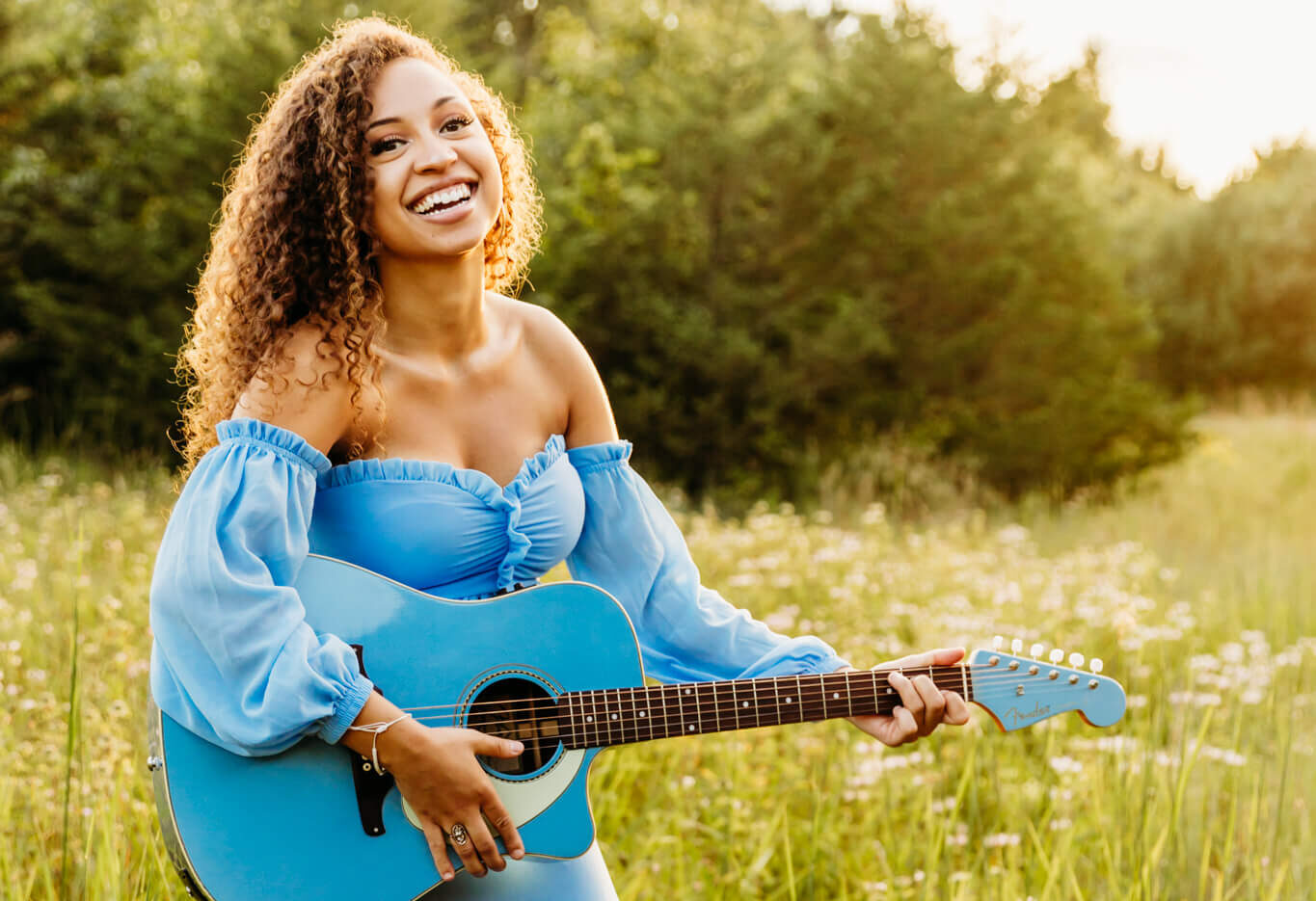 teen girl in a blue dress holding a blue guitar and singing in a park near Appleton