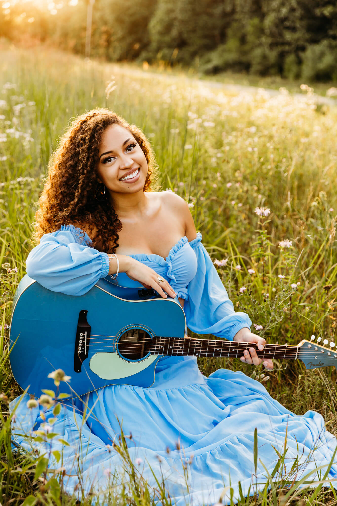 senior in a blue dress holding a guitar