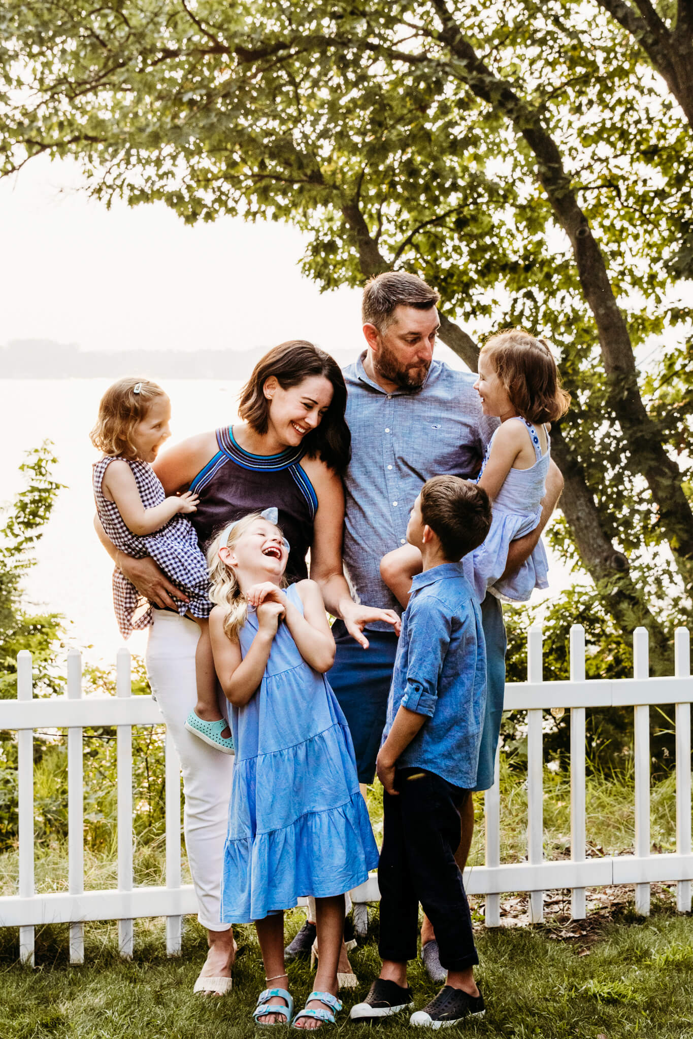 family laughing with each other by a fence by Ashley Kalbus Photography