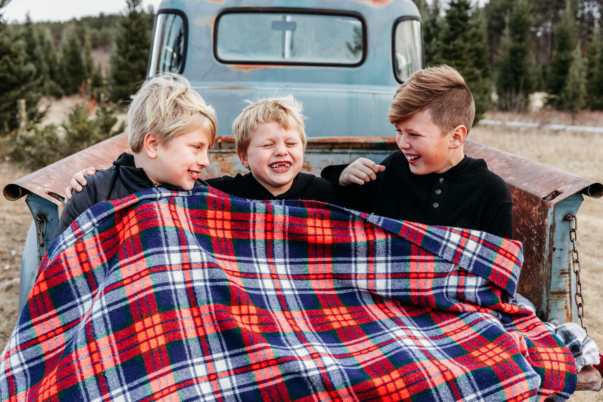 three brothers laughing together while cuddled in a blanket for blog post about spas in oshkosh