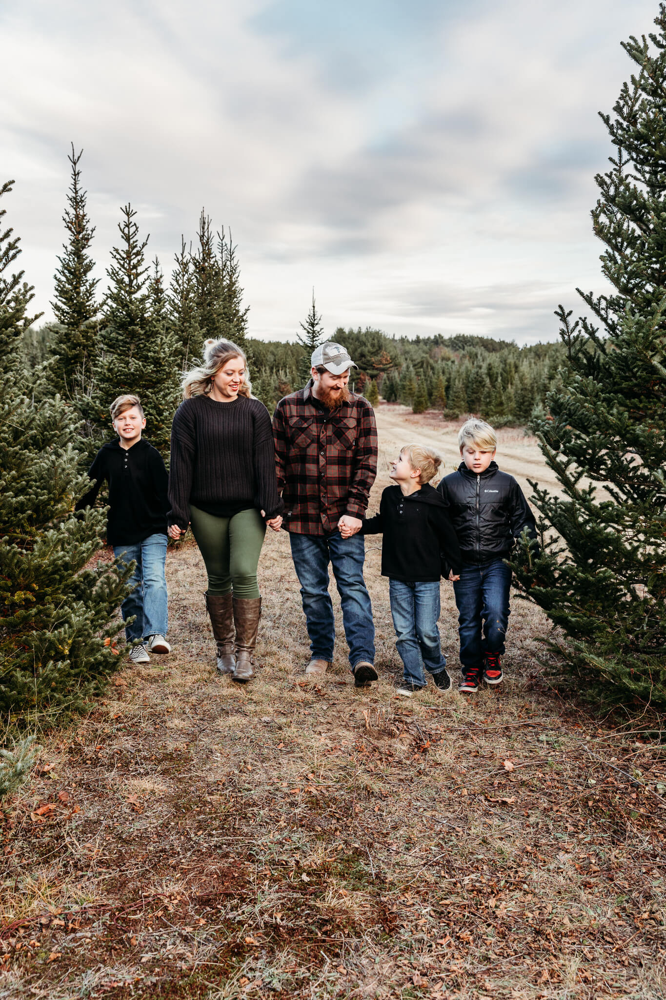 cute family walking together and laughing in the pine trees by Ashley Kalbus Photography