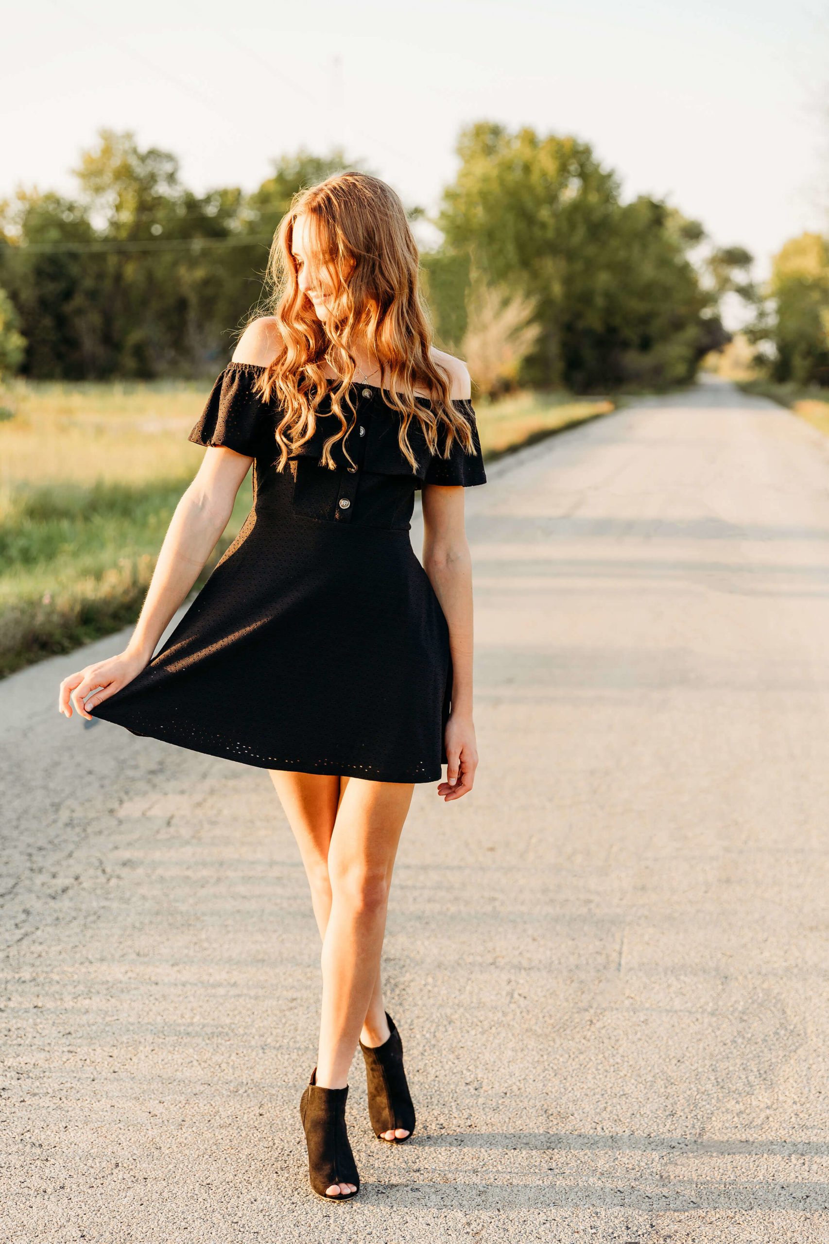 senior playing with her black dress on a road for her photo session by Ashley Kalbus Photography
