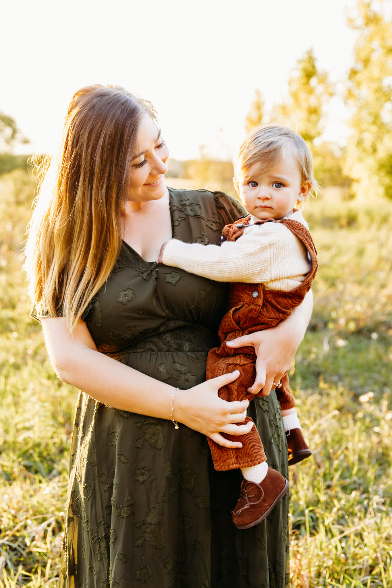 mom in a green dress holding her toddler during her family session