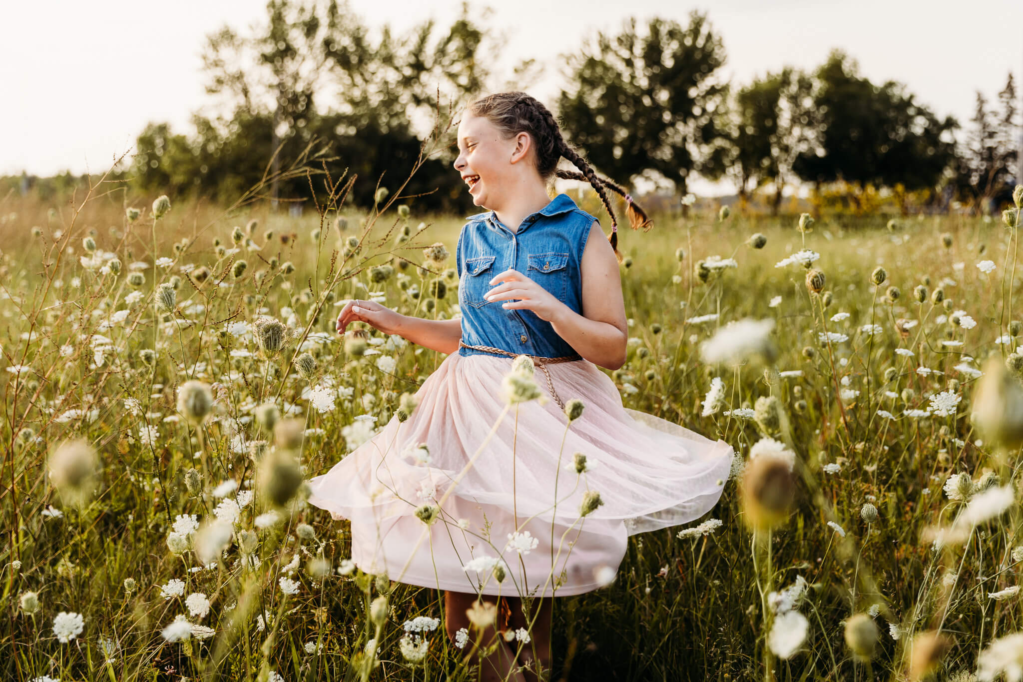 young girl twirling her denim and pink dress in a field of wildflowers