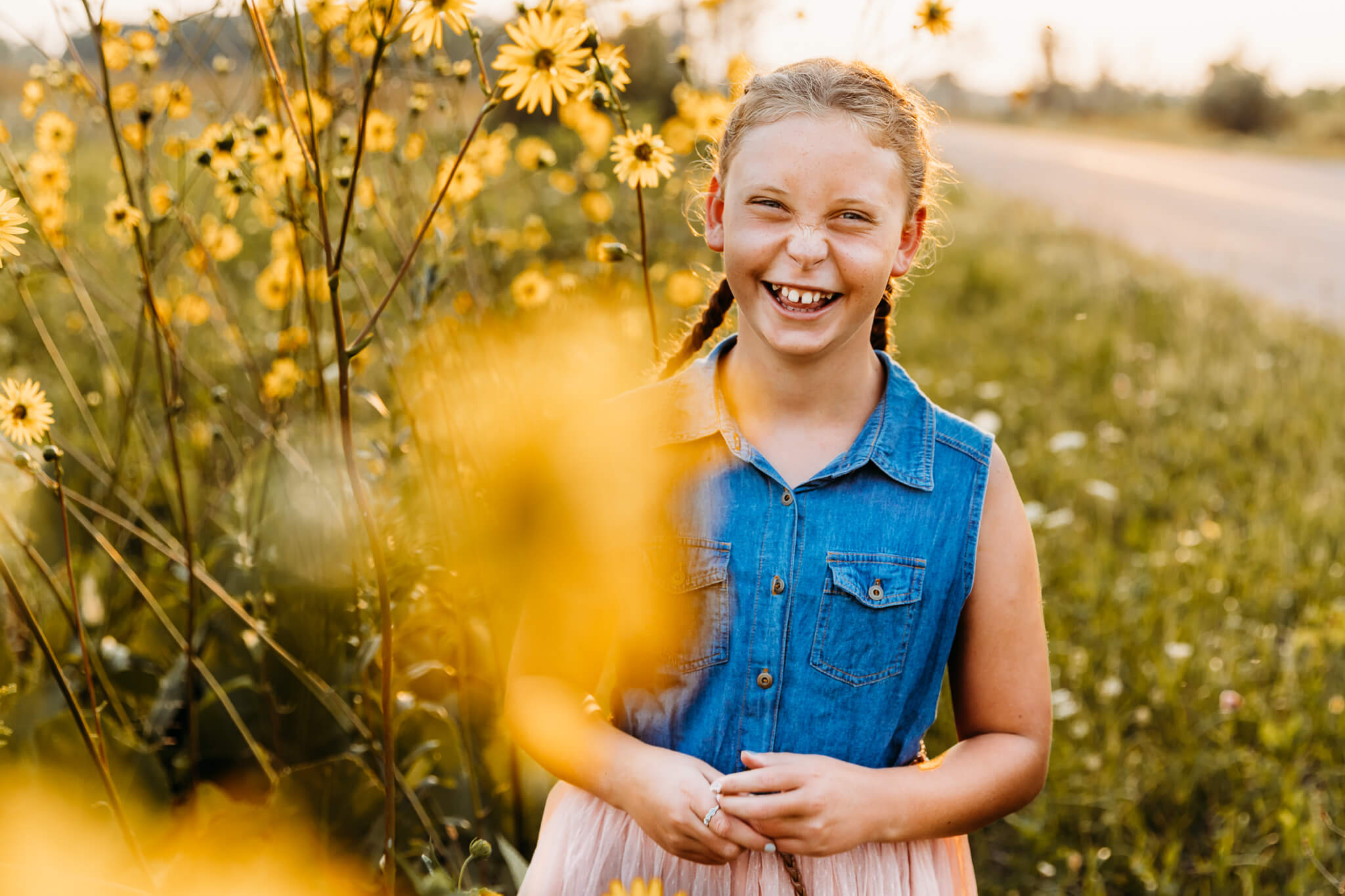 little girl laughing while standing in wild flowers