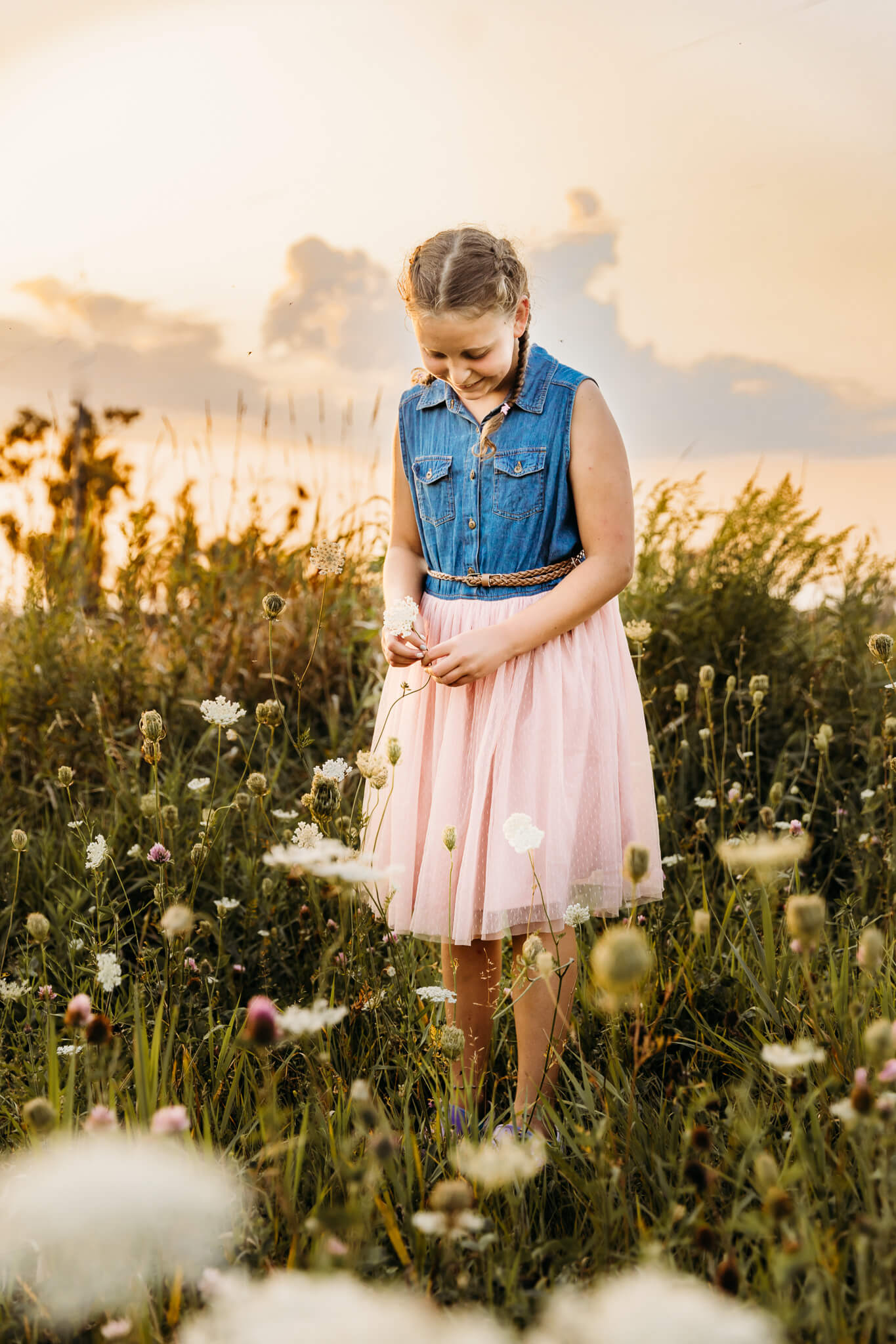 young girl looking down at wildflowers at sunset for blog about things to do in sheboygan