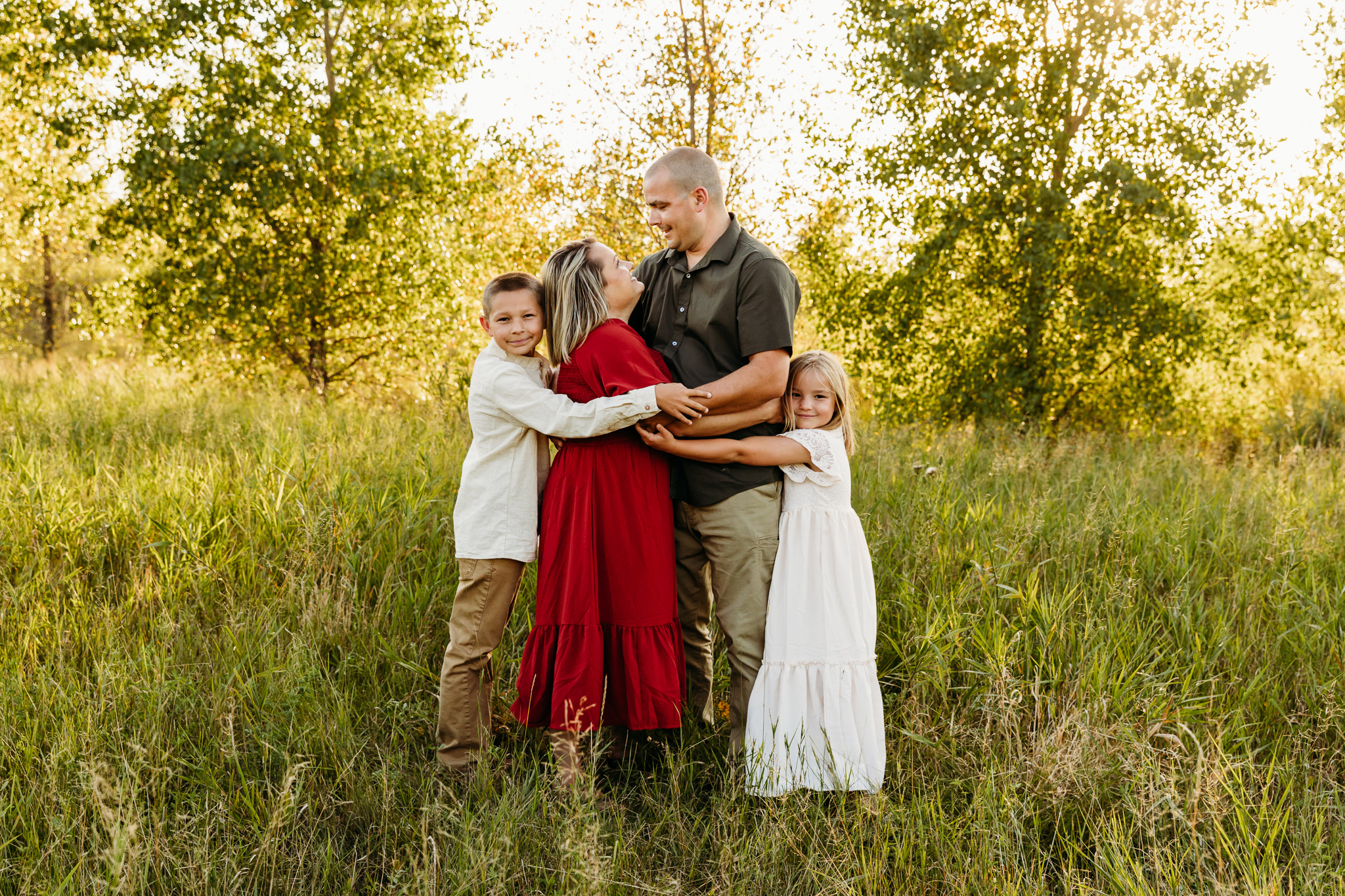 family of four hugging each other in a field