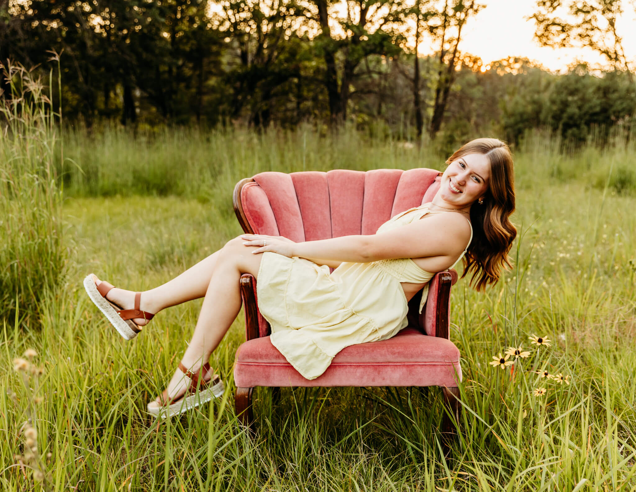 high school senior sitting in a pink chair and smiling