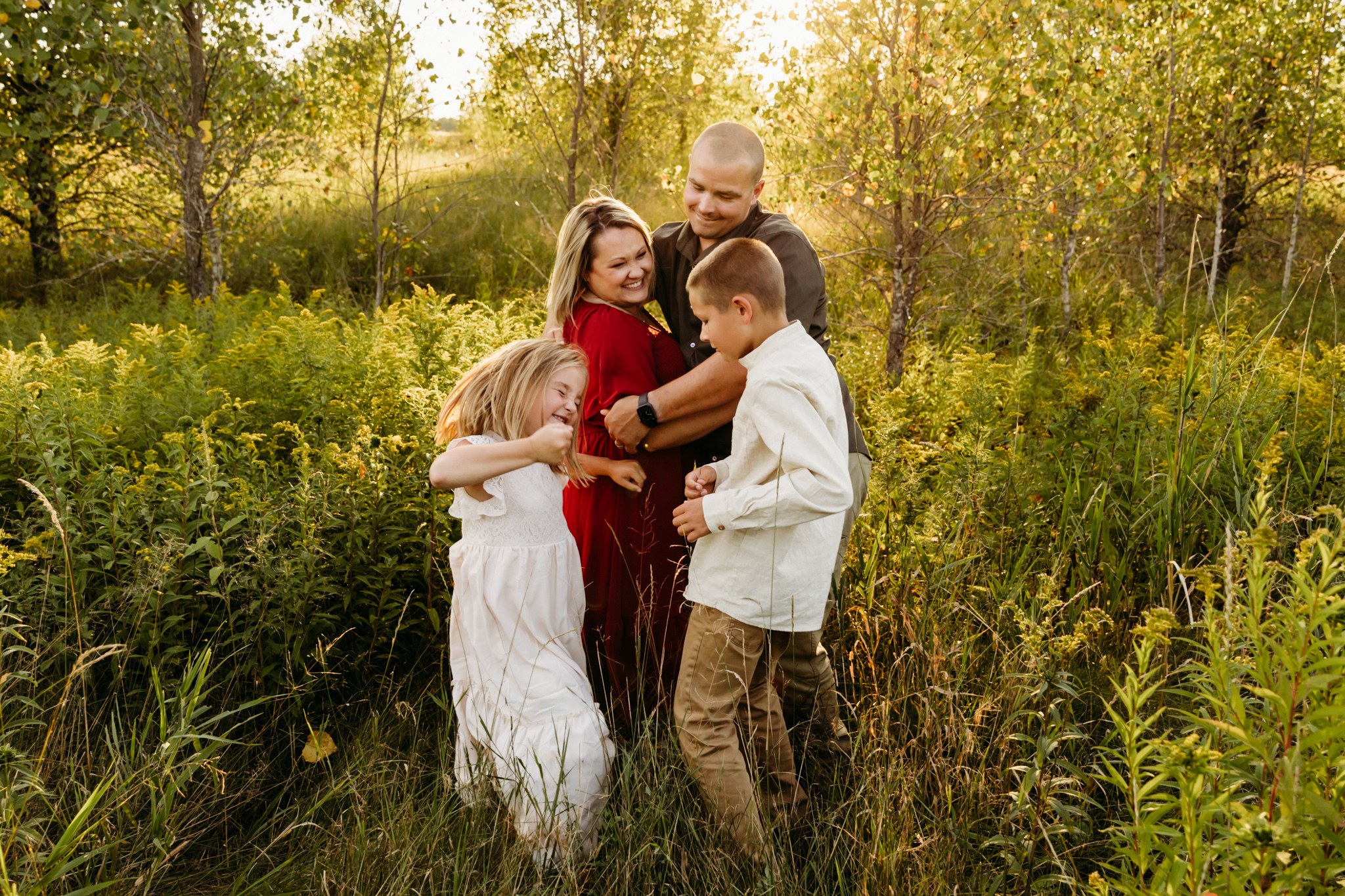family of 4 laughing and playing in a field near Green Bay