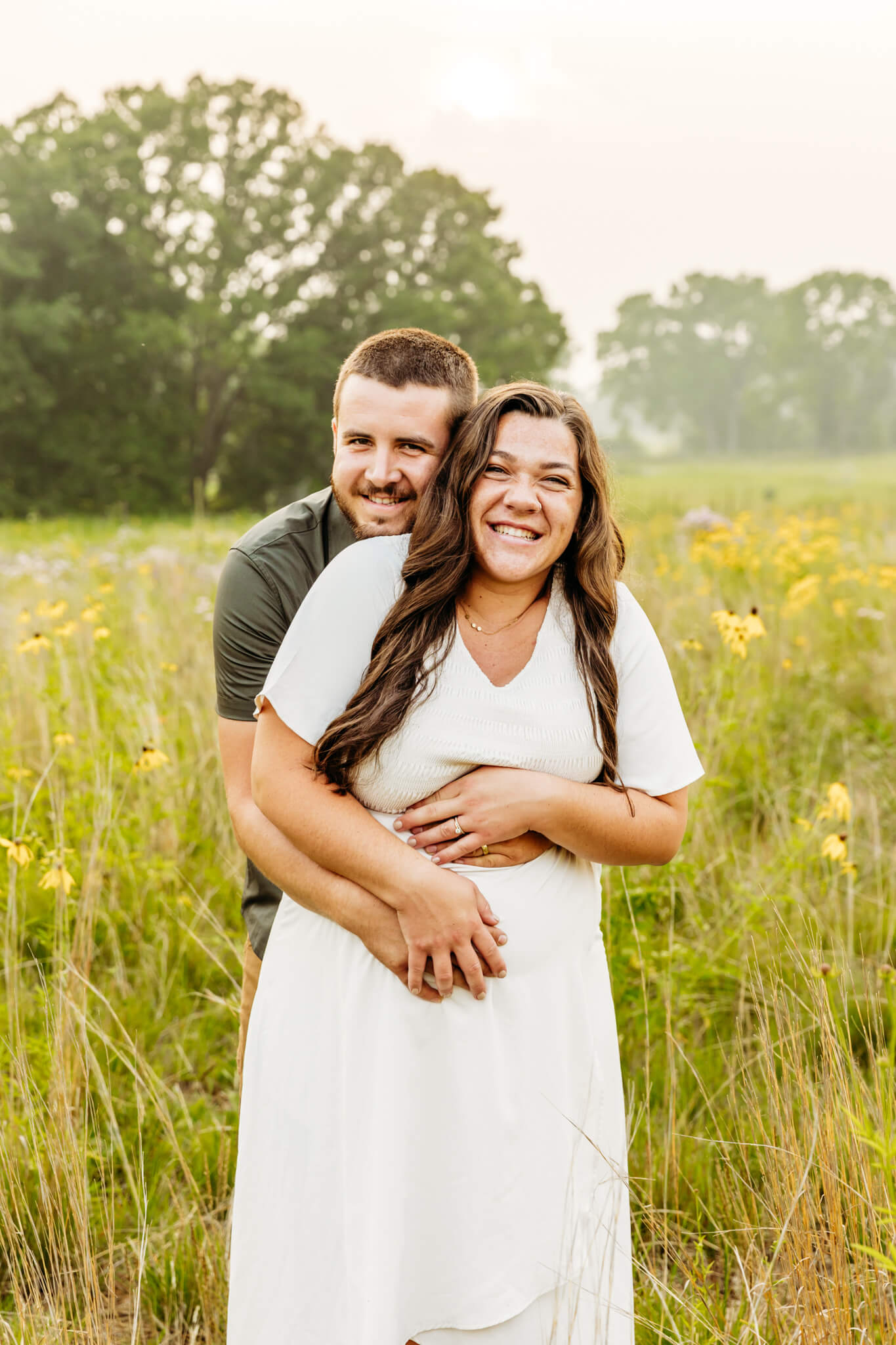 husband surprising his wife and hugging her from behind during their maternity session