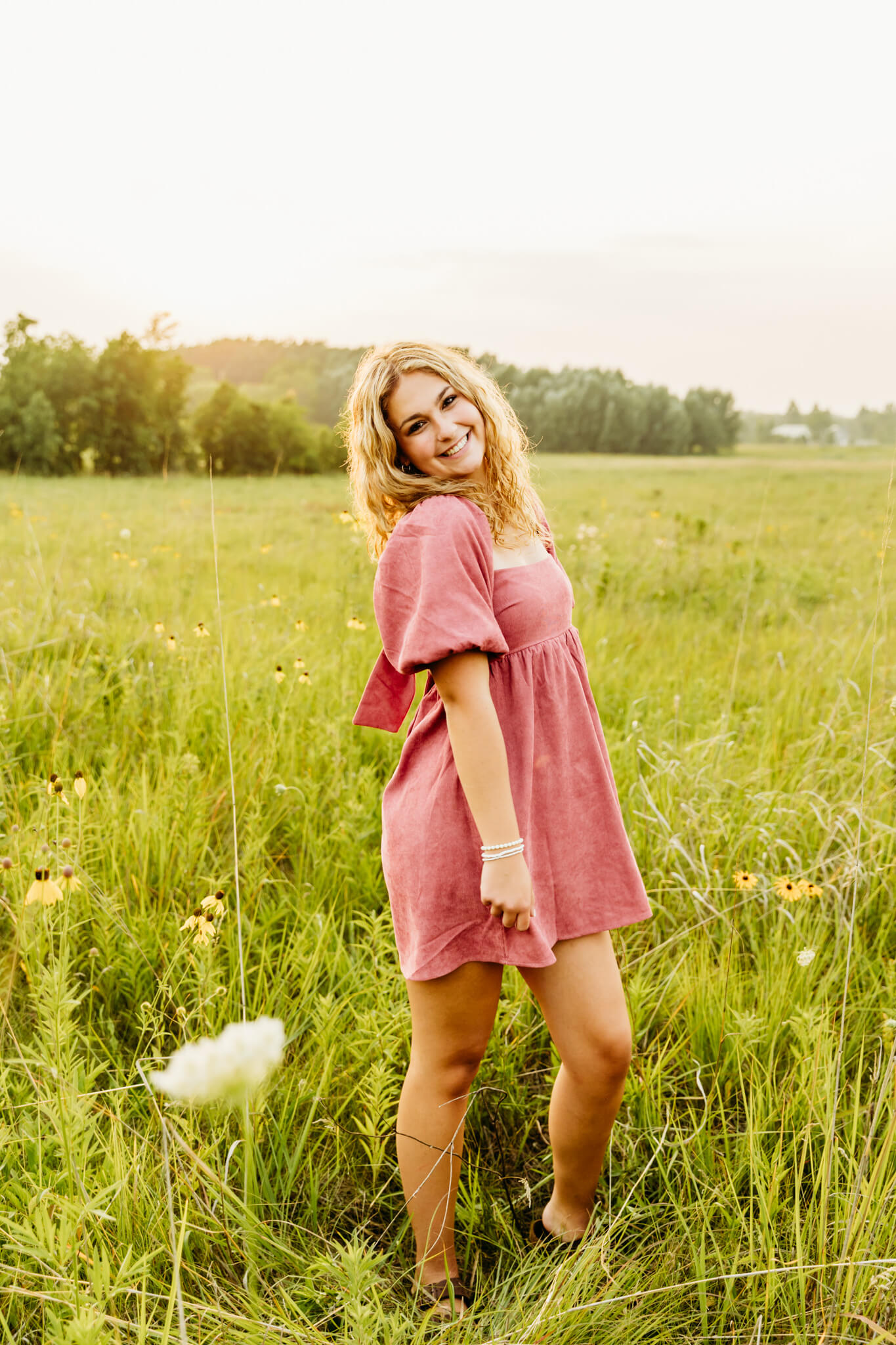 stunning teen girl standing in a field of wild flowers with a gorgeous hair cut from a hair salon in Fond Du Lac