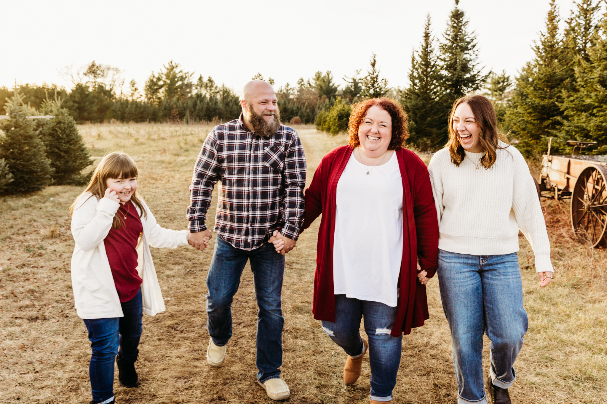 family of 4 laughing and walking through a field