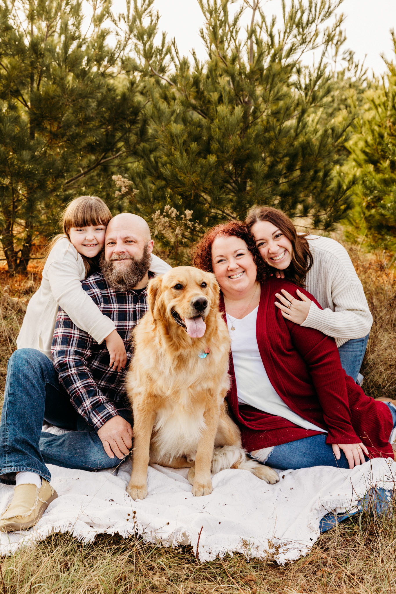 family of 4 and their dog sitting on a blanket
