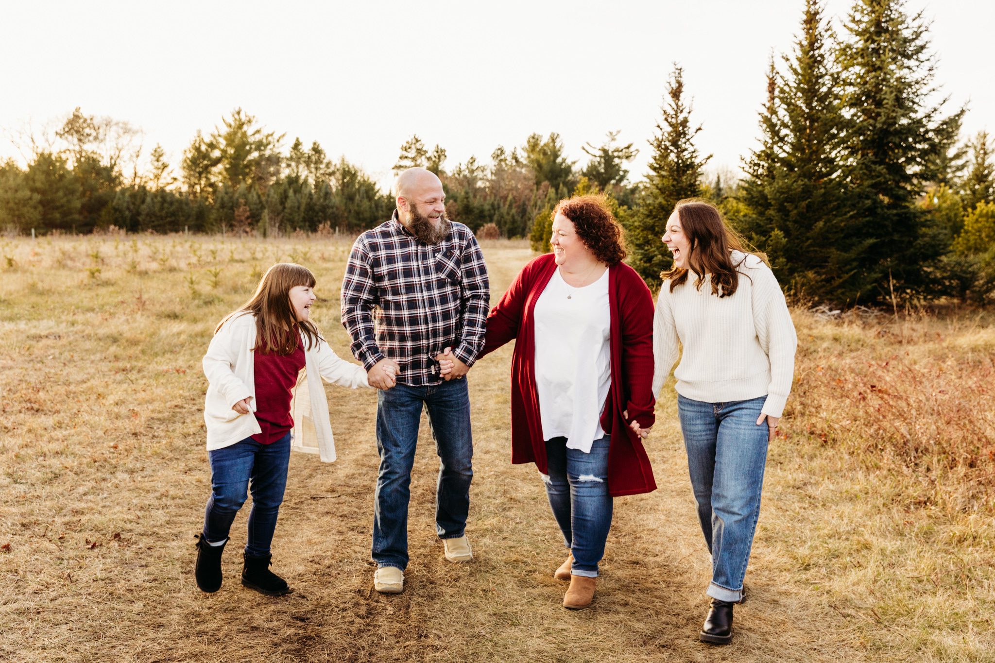 family of 4 laughing and walking through a christmas tree farm things to do in egg harbor wi