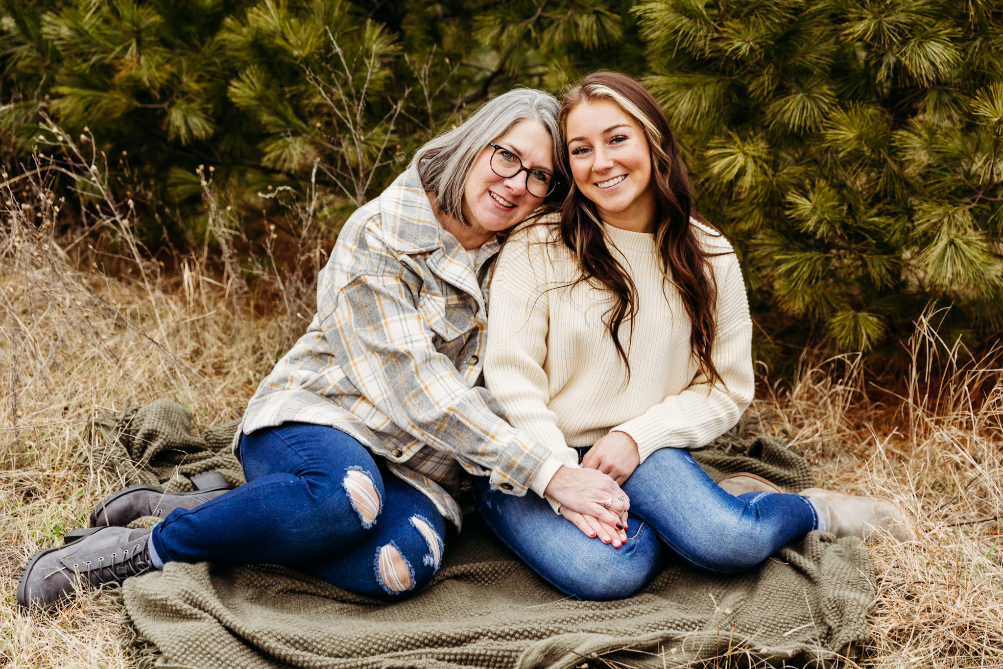 mother and daughter sitting on a blanket in a field leaning on each other spas in Green Bay