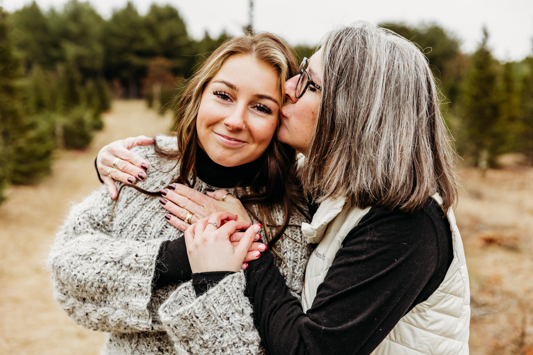 mom kissing her daughter on the cheek in a field