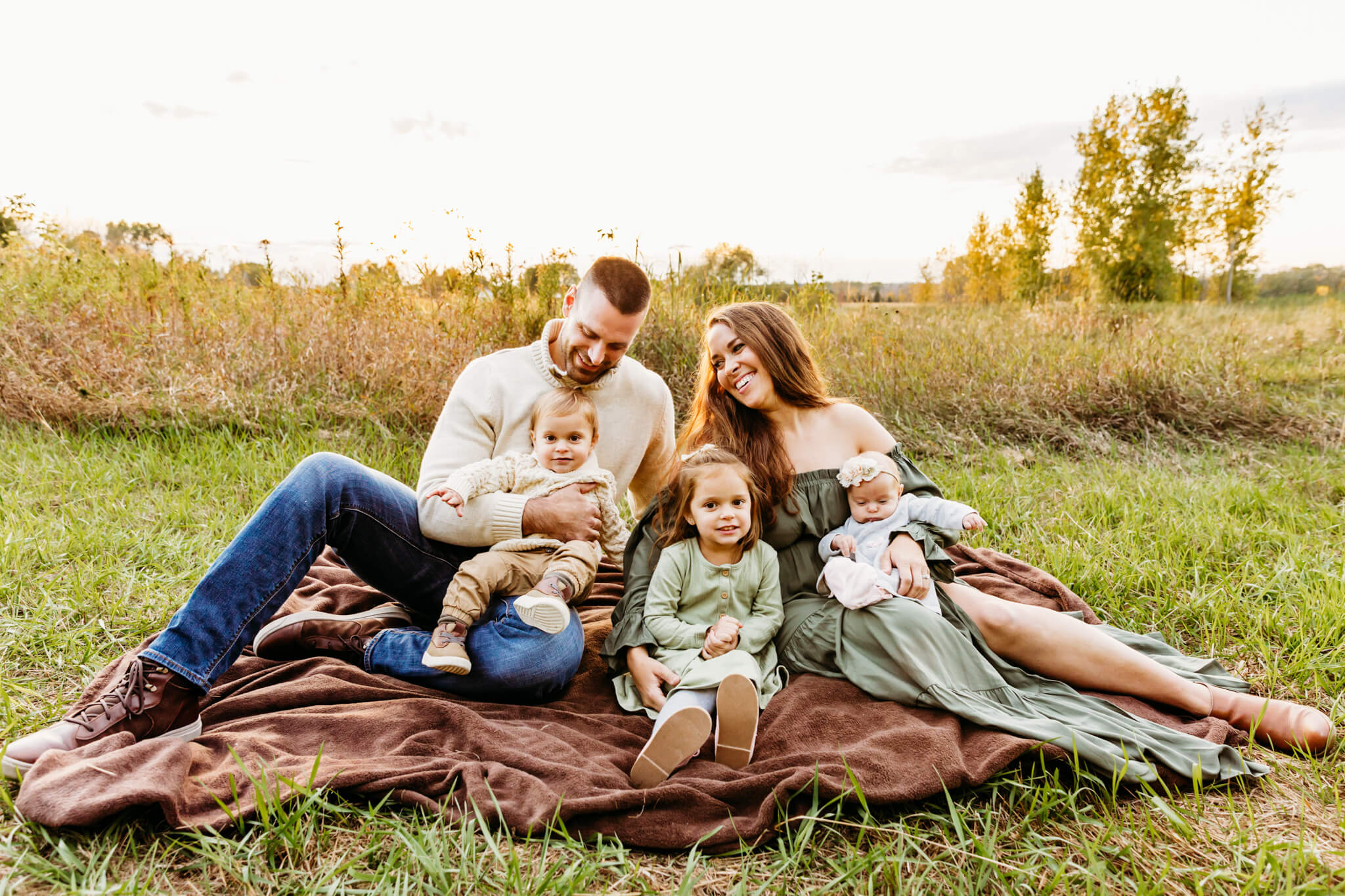family of 5 snuggling in a field at sunset near Green bay WI