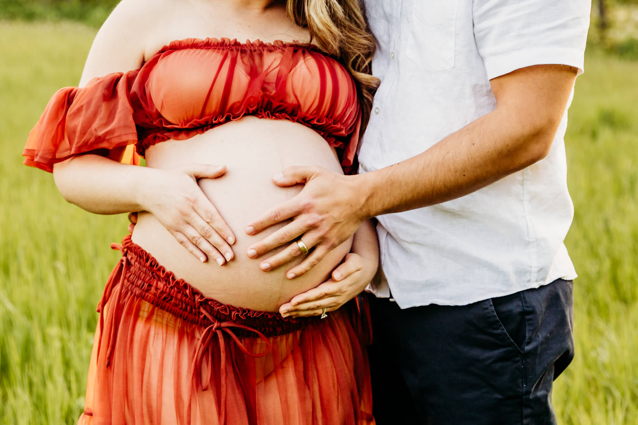 close up of an expecting mama's baby bump as her and her husband each put their hands on her belly