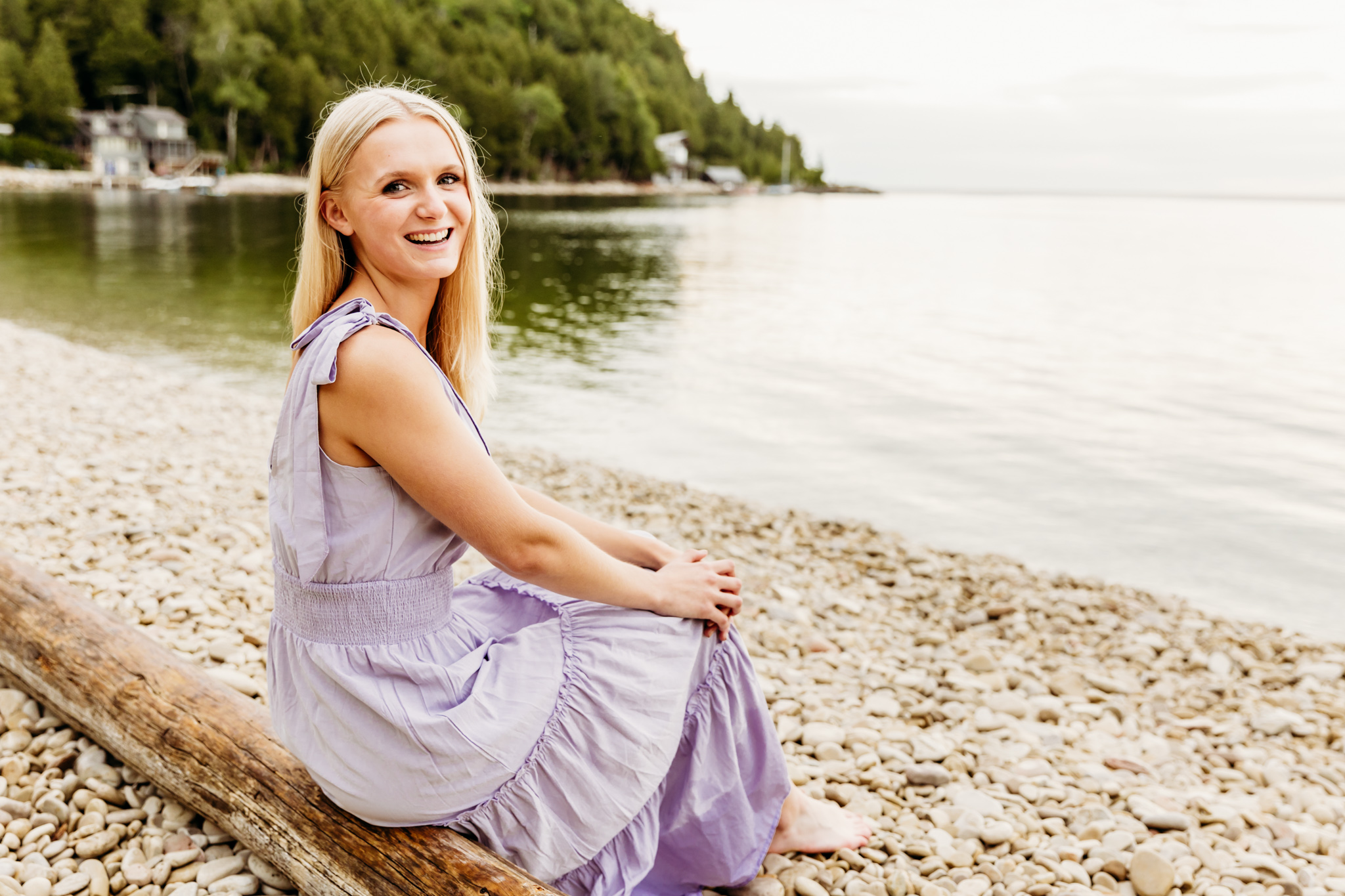 gorgeous teen sitting on a log on a beach in egg harbor