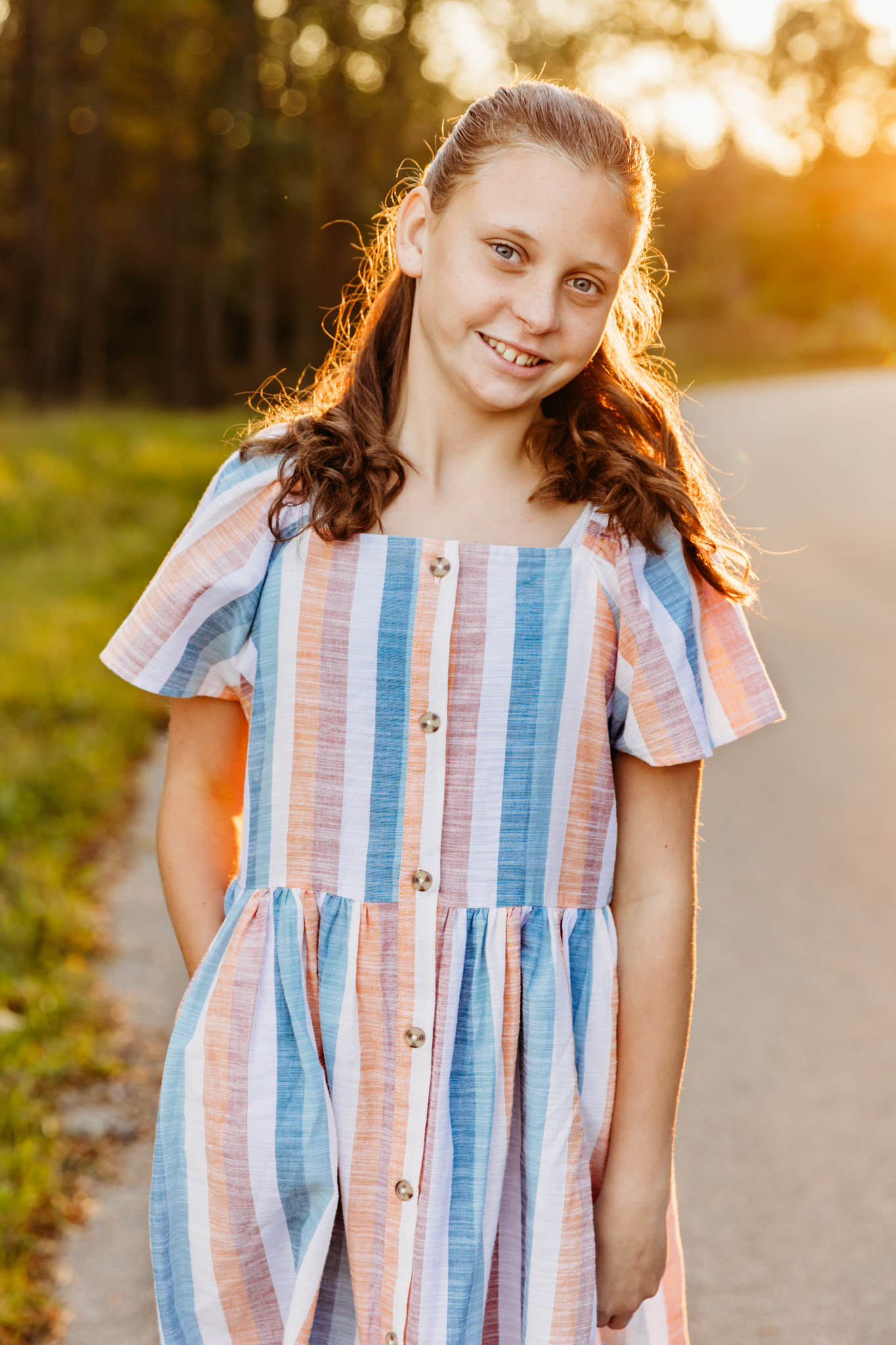 A young girl stands on a walking path at sunset in a striped dress things to do in Fond du lac