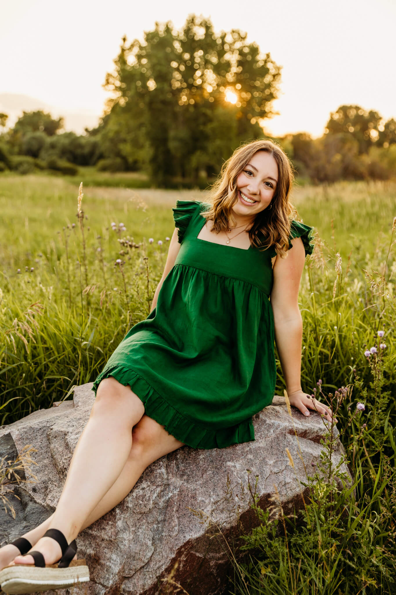 teen girl in green dress sitting on a large rock in a field at sunset near Appleton