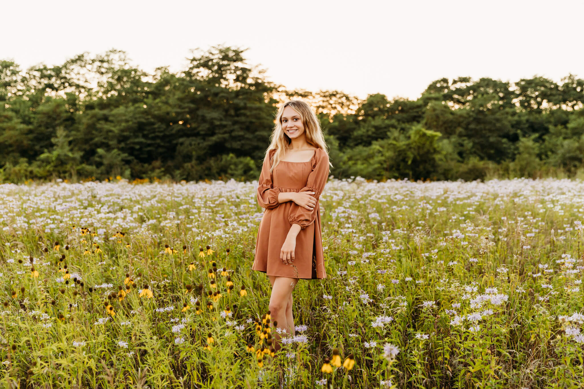 gorgeous teen in an orange dress standing in a field of wildlfowers at sunset near Oshkosh