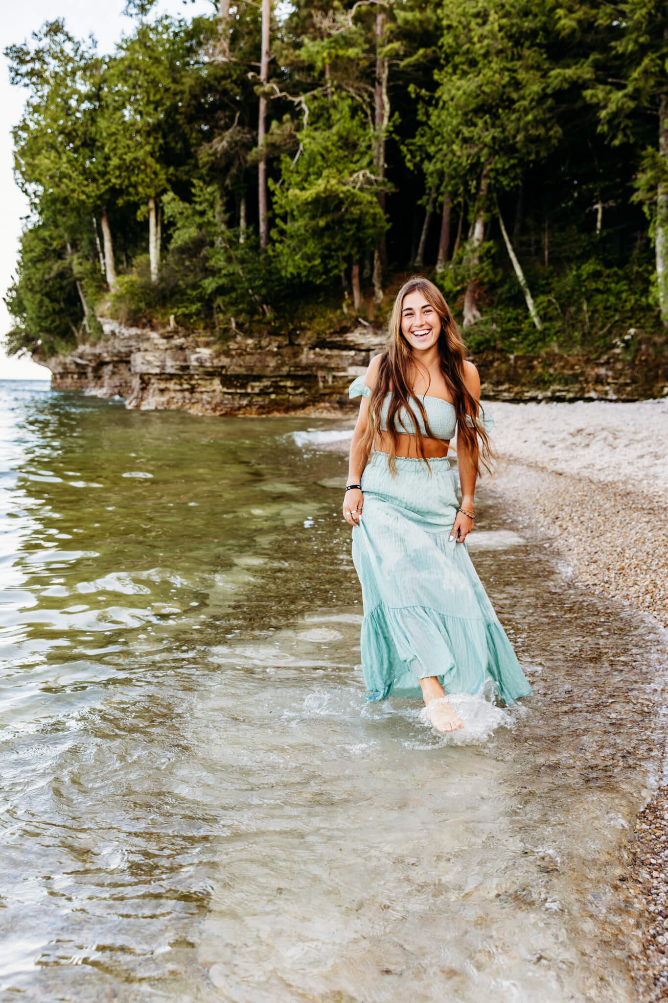 brown haired teenage girl kicking her feet in the water for her Ashwaubenon High School senior photos