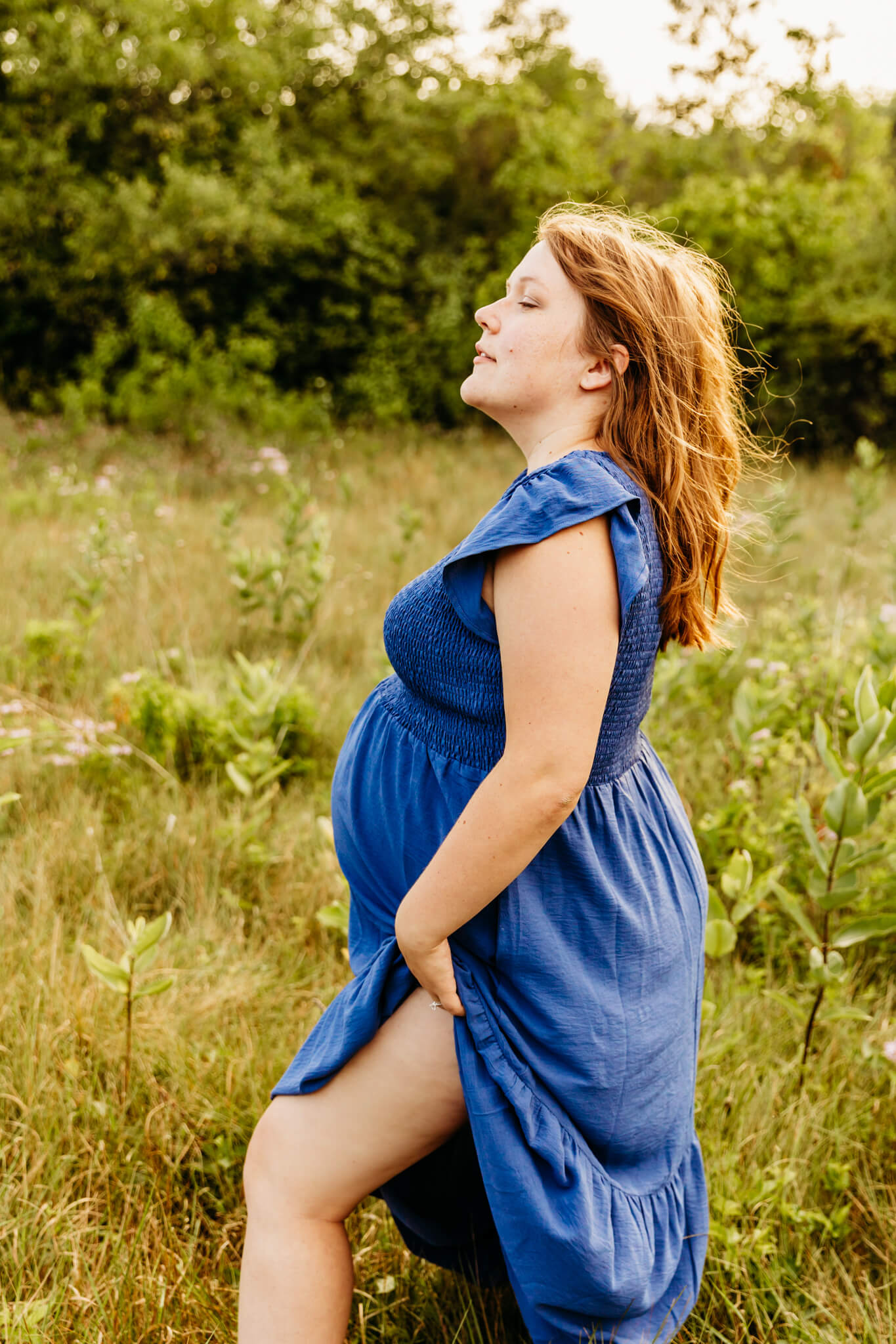 expecting mom in a blue dress looking off into the distance for blog post about green bay massage therapy