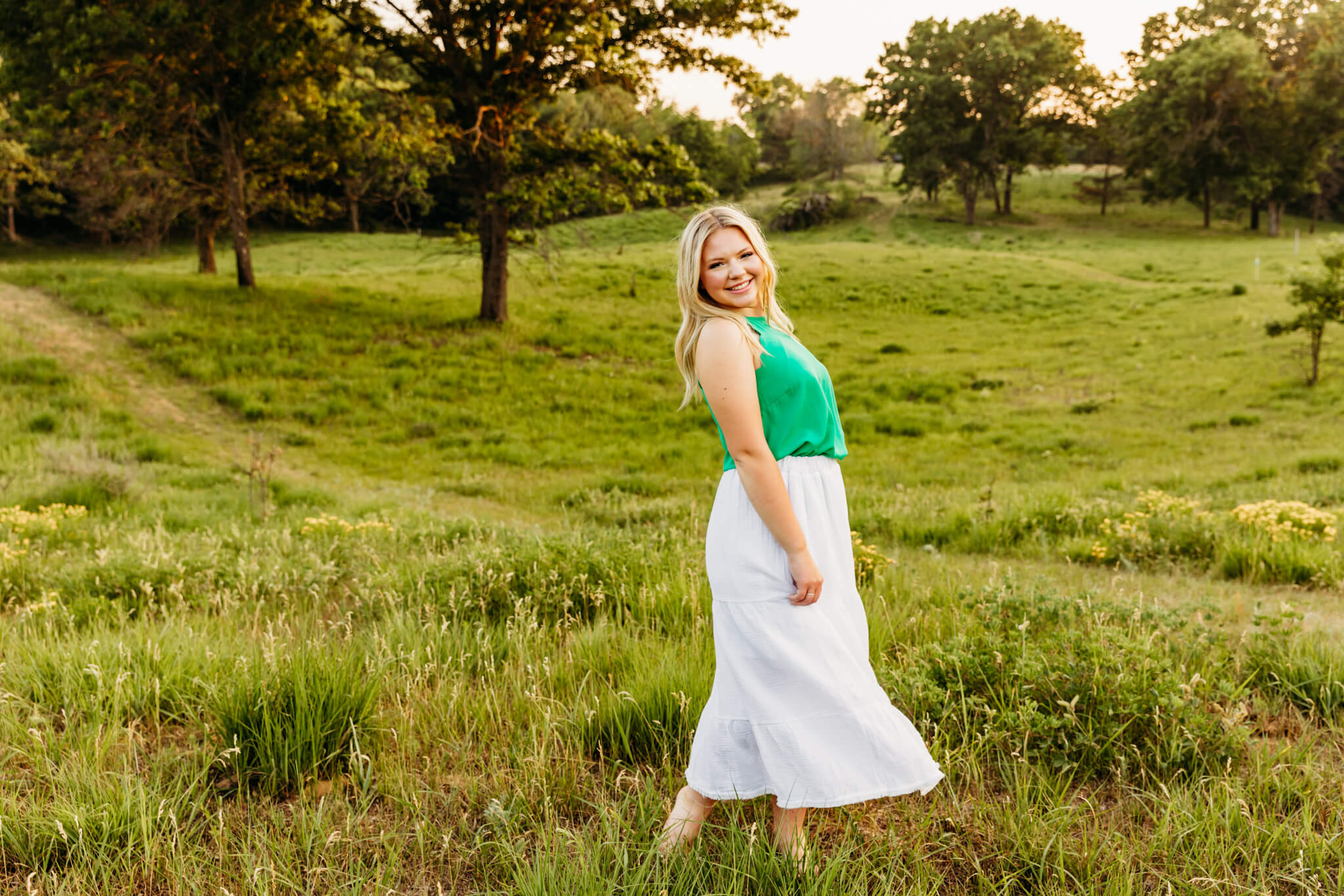 blonde teenager in a white skirt and green top dancing in a field near Oshkosh