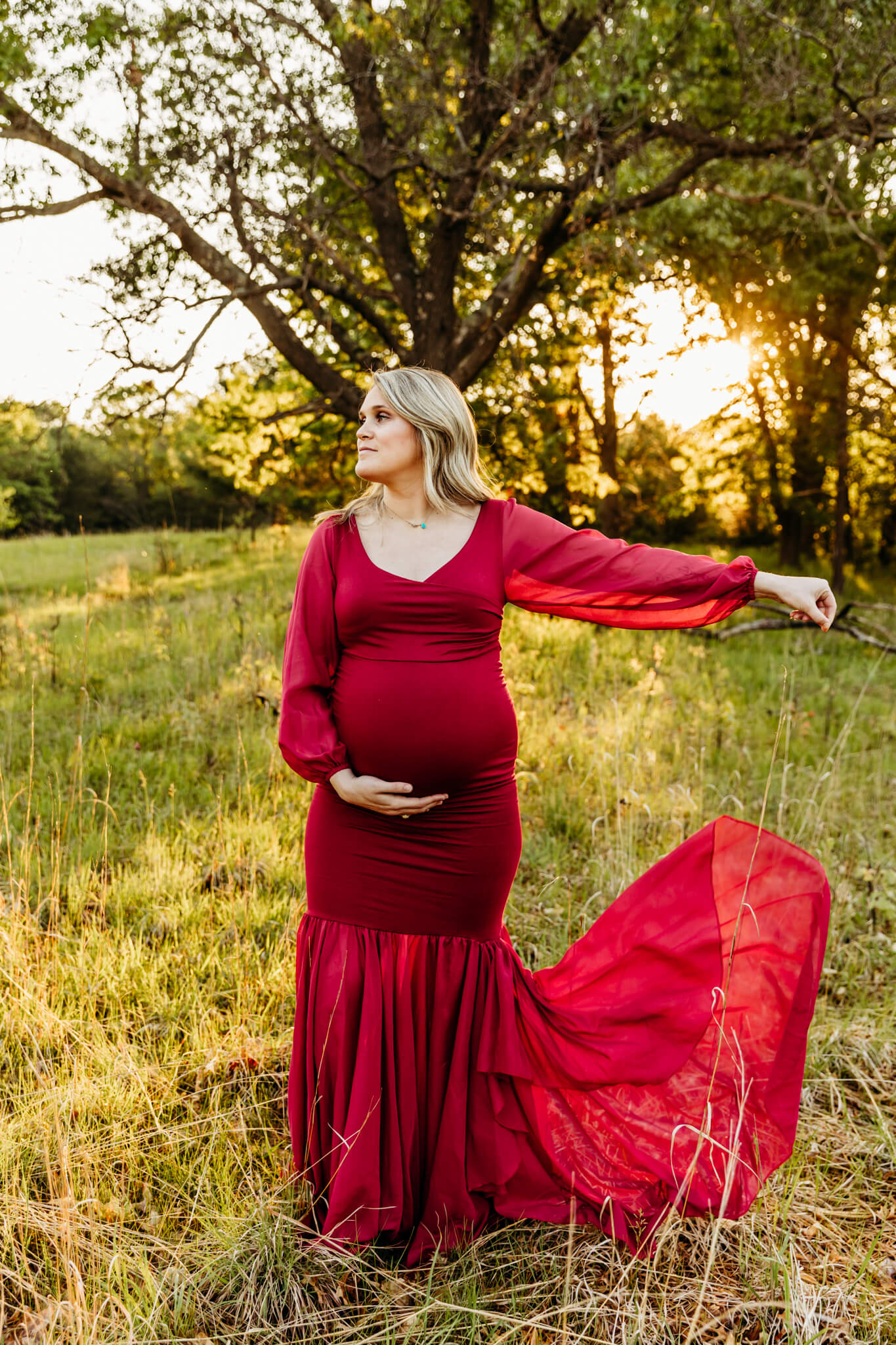 pregnant woman playing with her red gown as the sun sets behind her for blog post about Childrens Products LLC
