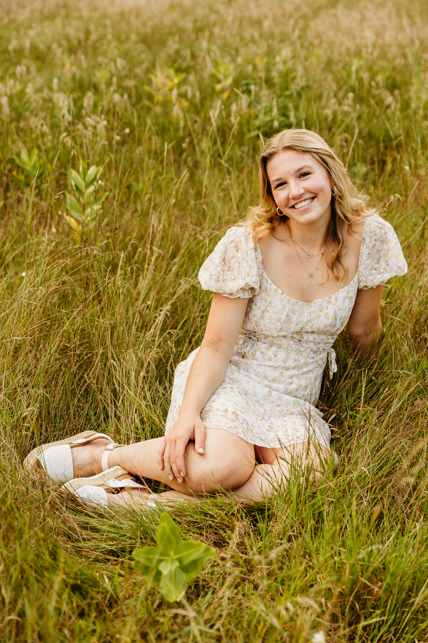 beautiful teen sitting in a grassy field near oshkosh