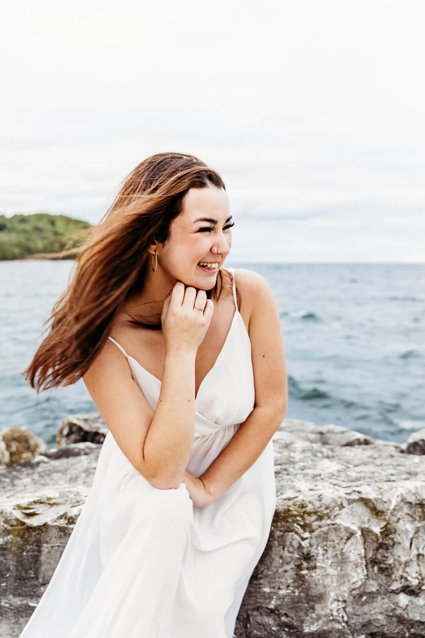 teen girl leaning forward and resting chin on her hand as she laughs during her senior session in Door County