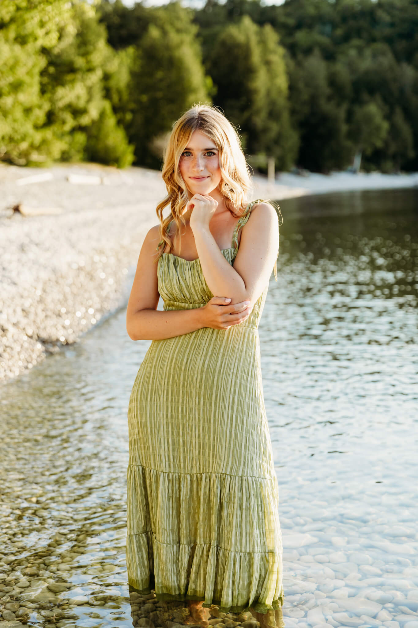 beautiful blonde teen girl standing in the clear water in a green striped dress and resting her chin on her hand for a blog post about Lilly Lo