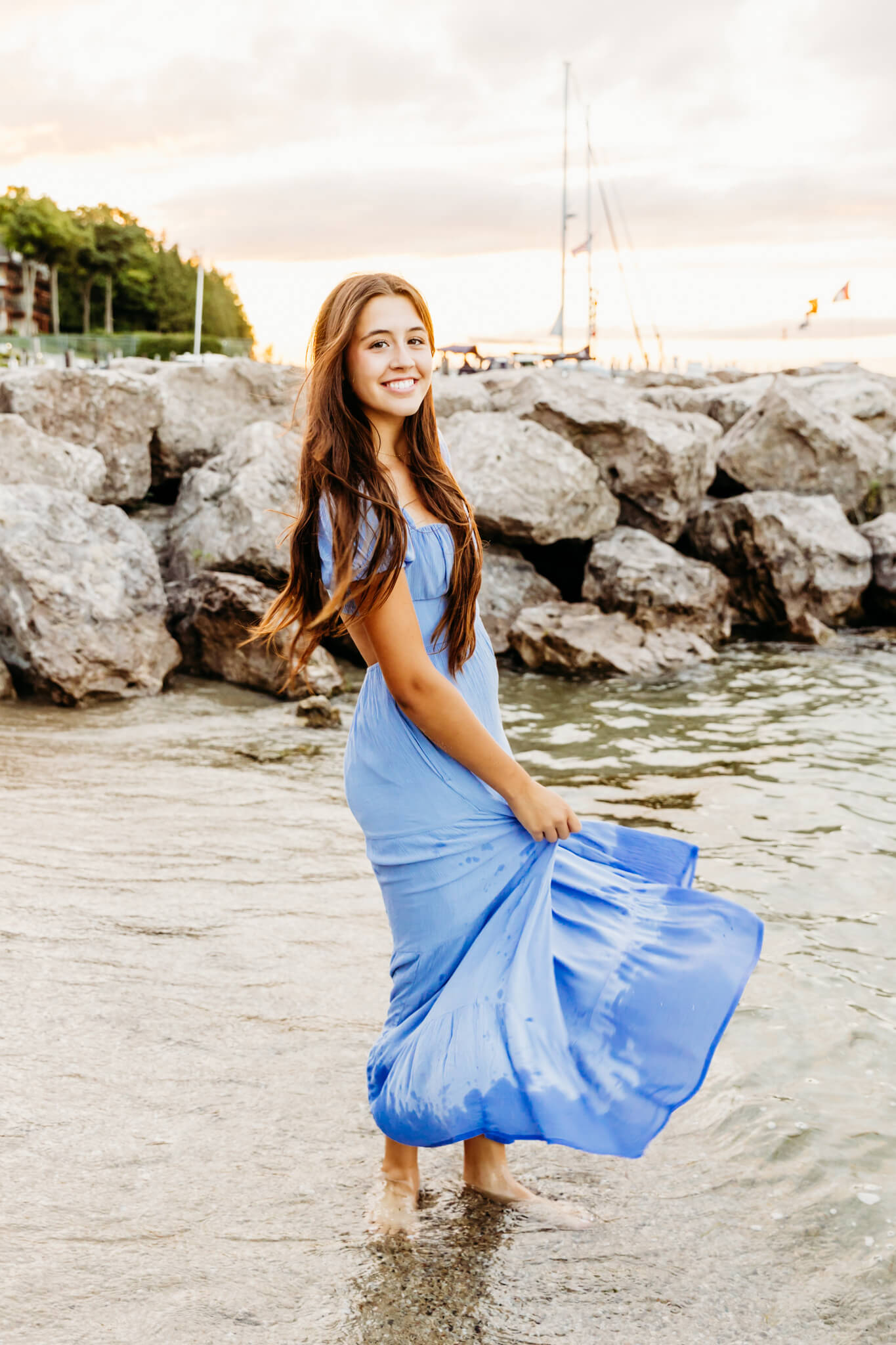 brown haired teen girl twirling in her light blue dress as she stands in Lake Michigan during her Door County senior photo session