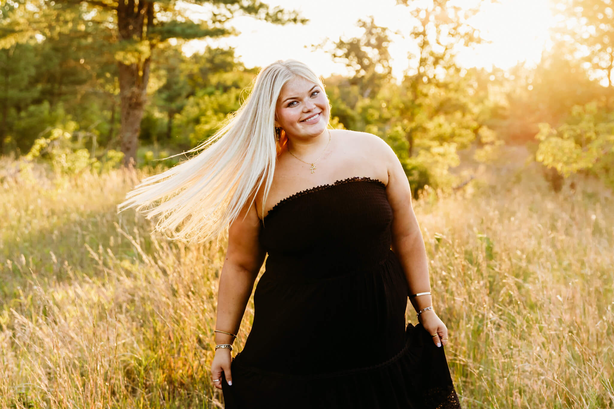 beautiful teenage girl in a black dress spinning in a field as her hair flies in the wind at golden hour near Green Bay