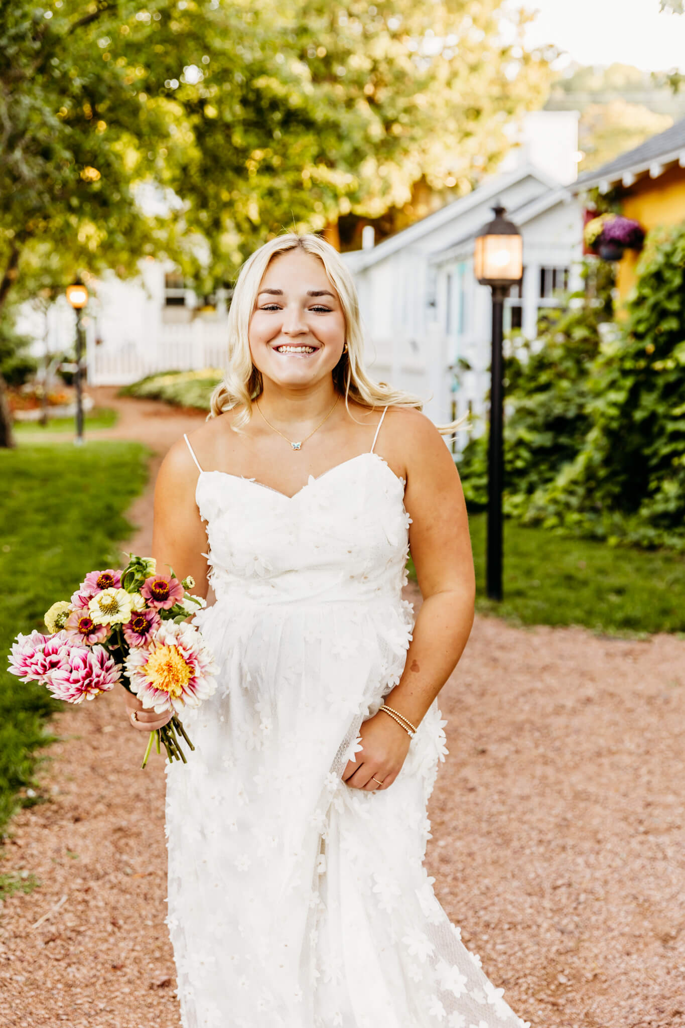 teenage girl in a white floral dress laughing as she holds a bouquet of flowers while walking by boutiques in Door County