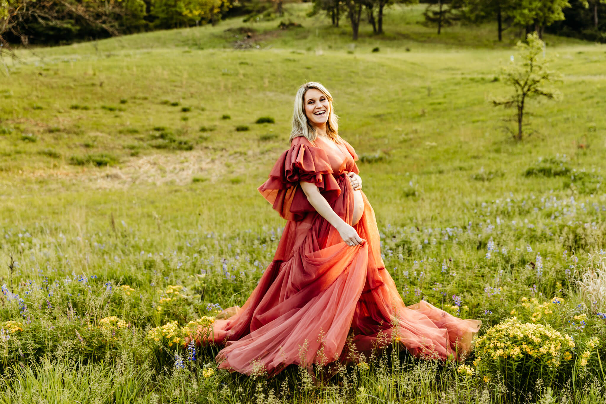pregnant woman dancing in a big gown in a flower field