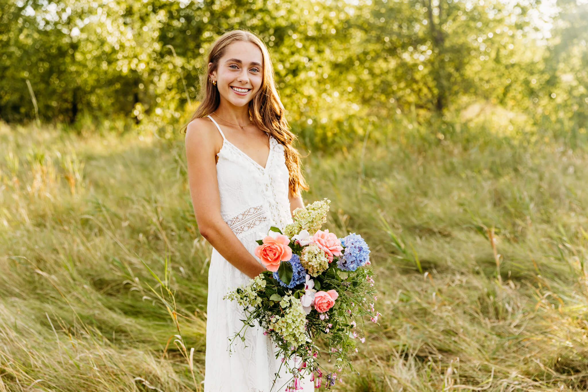 teenage girl holding a flower bouquet and smiling for her senior photos