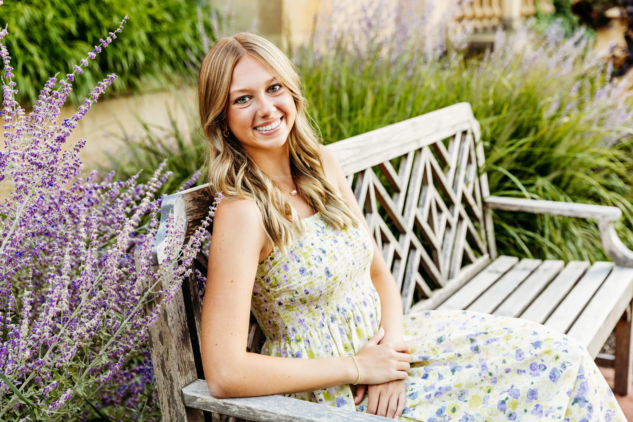 Pretty teenage girl in a floral dress sitting on a bench in a garden at Paine Art Center