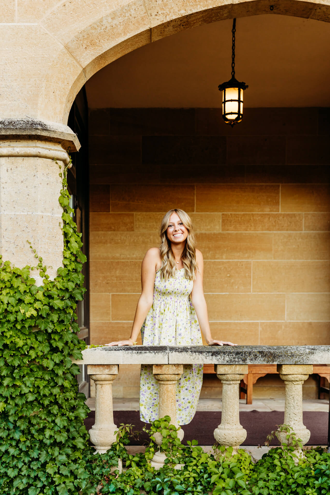 young woman standing in an archway and resting her hands on the cement railing