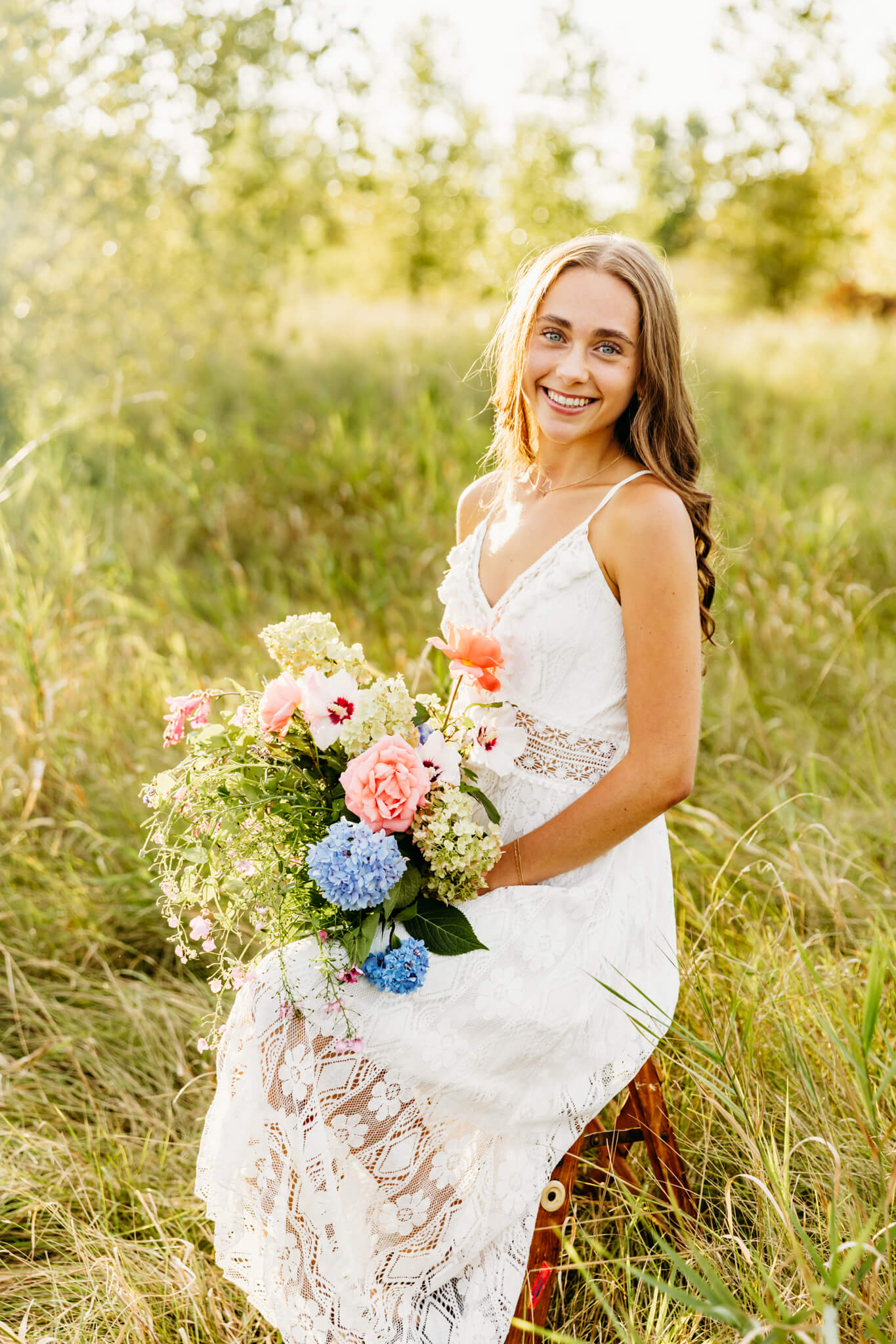 gorgeous teen girl sitting on a small ladder and holding a bouquet created by Events Everlasting in New London