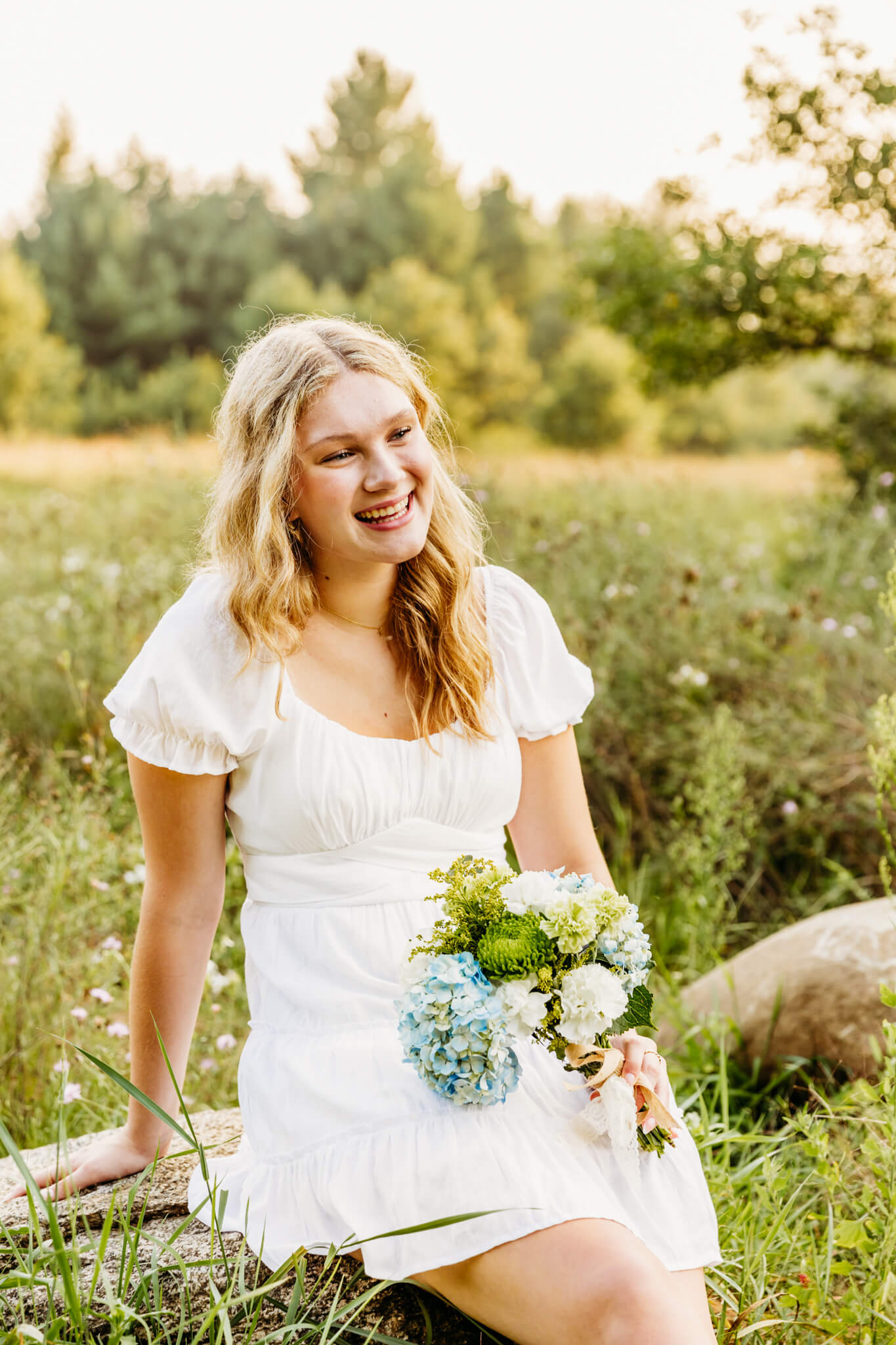 Teen girl from New London holding a bouquet of flowers and laughing during her senior session