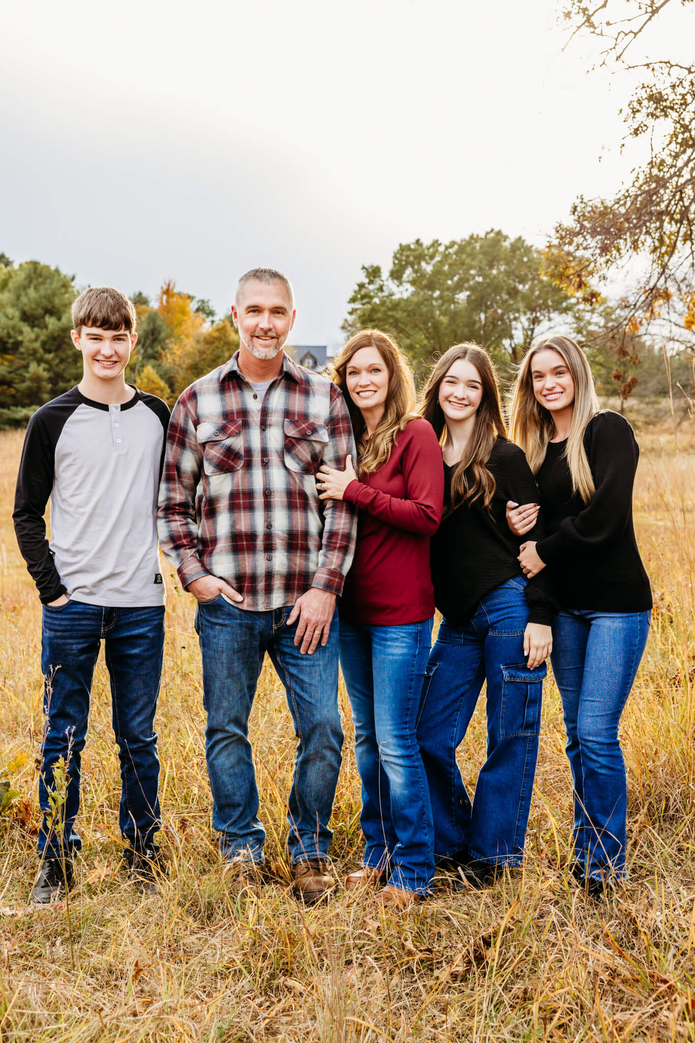 Beautiful family of five standing in a field during the fall season for a blog post about apple orchards in Appleton Wi