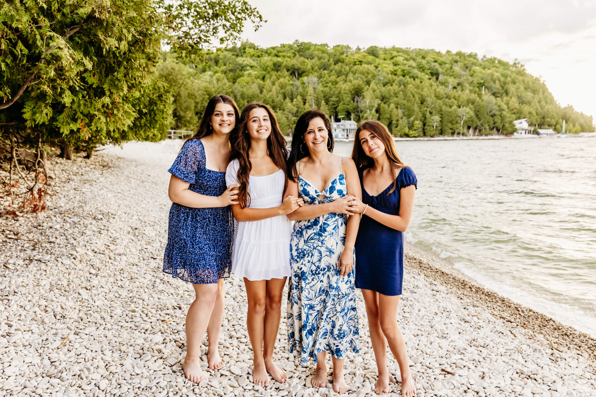 beautiful image of a mom and her daughters dressed in blue and white standing on a gorgeous rocky beach near Fish Creek.