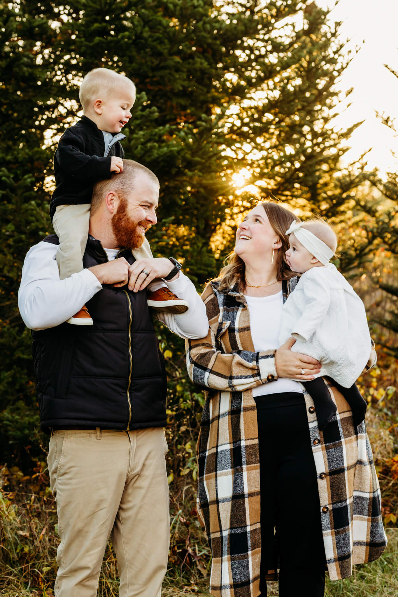 toddler boy riding his dad's shoulders as mom holds his baby sister and looks up at him.